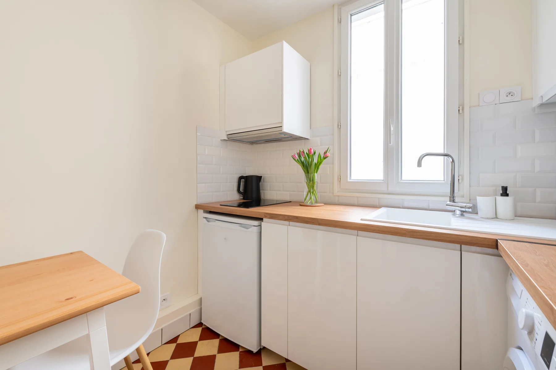 A bright kitchen with a sink beneath a tall window.
