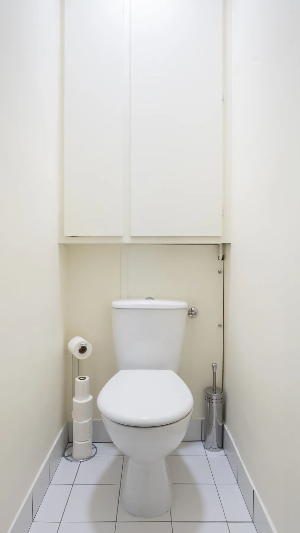 A bathroom with a toilet beneath a wall cabinet.