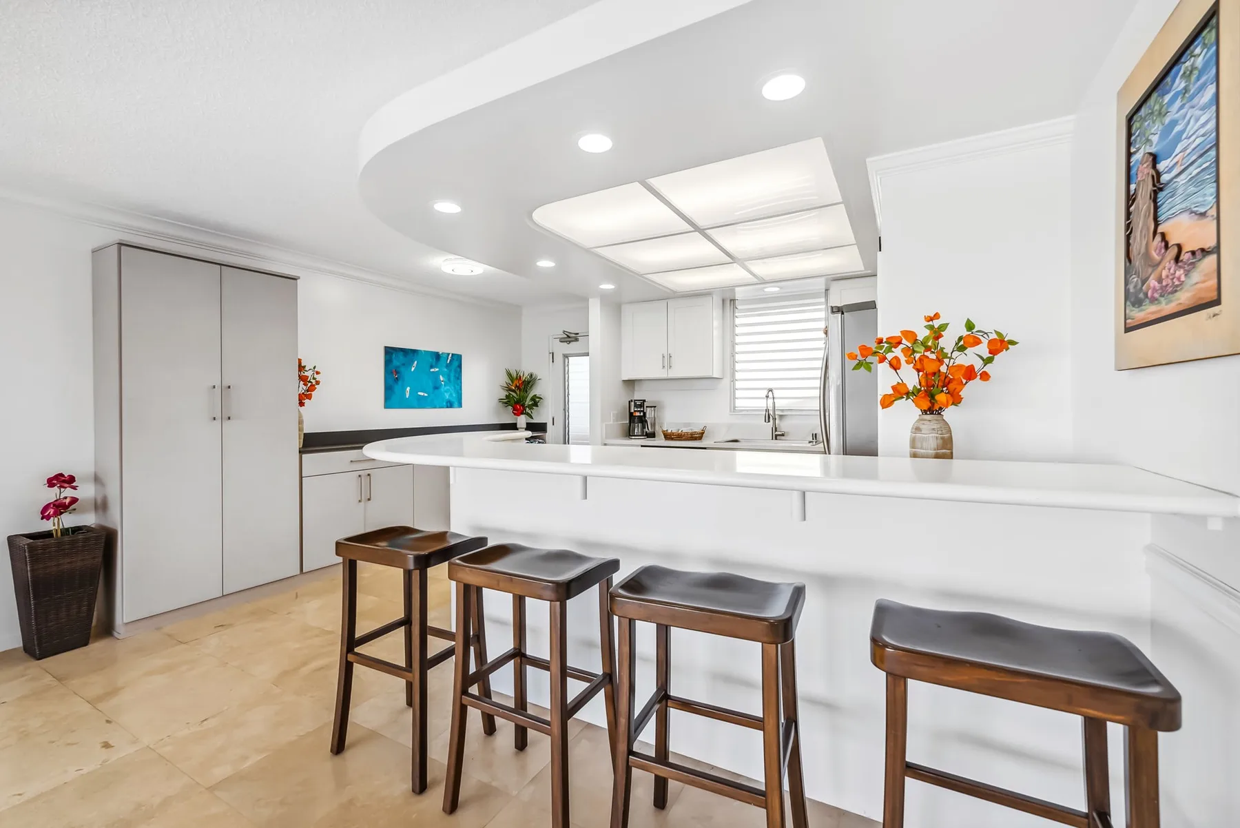 Una cocina luminosa con una barra blanca y asientos de madera.