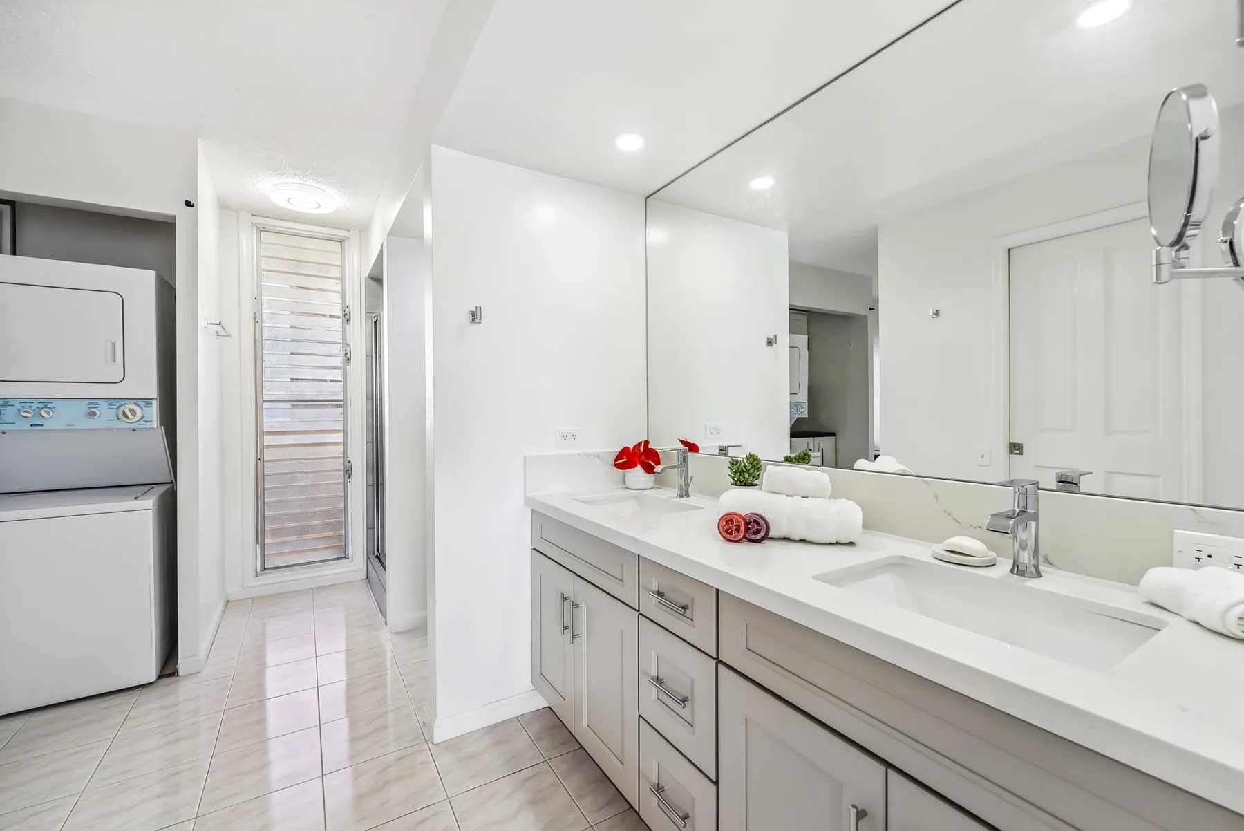Un baño luminoso con un tocador largo, un espejo amplio y electrodomésticos de lavandería.