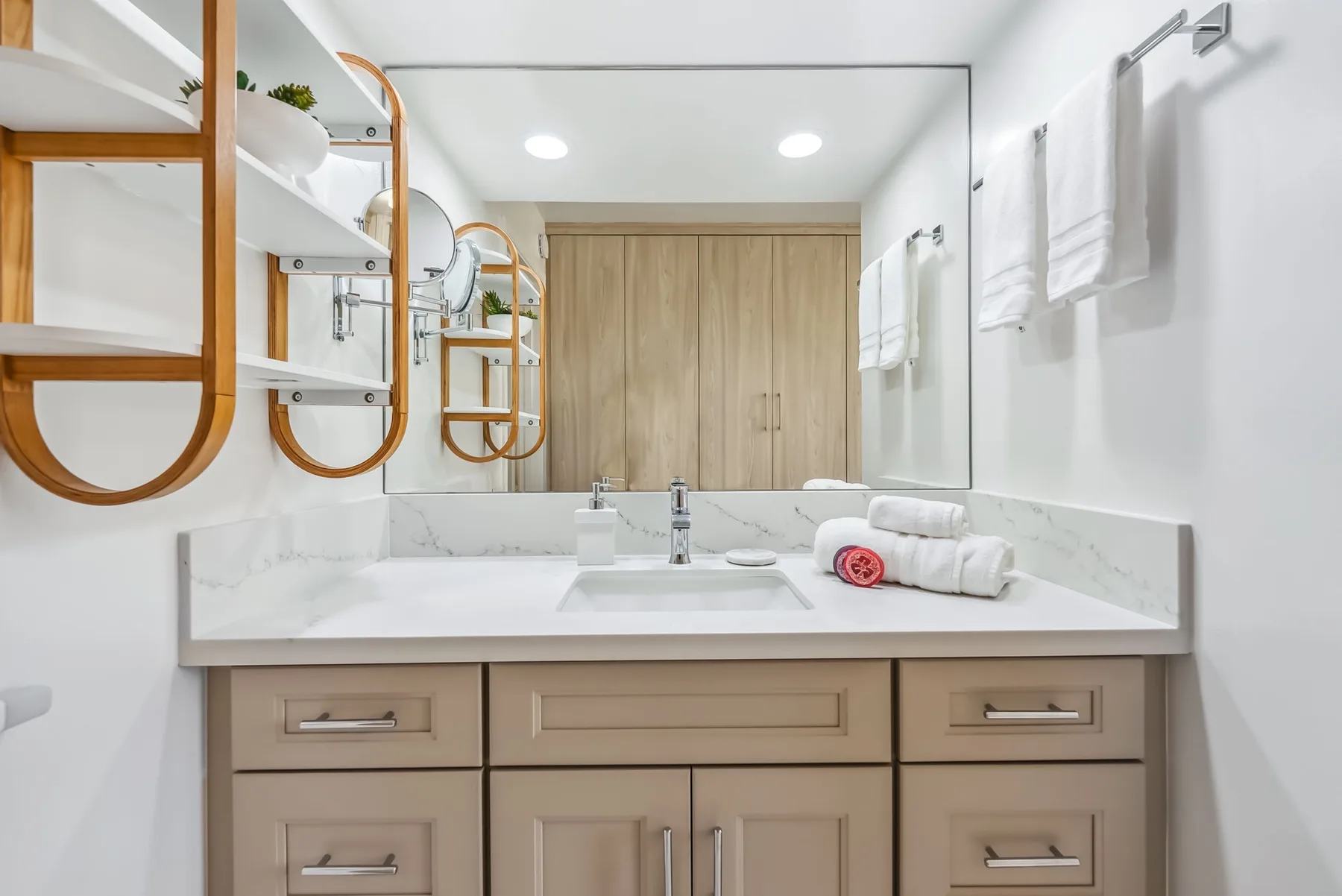 Un tocador de baño luminoso con lavabo, espejo y toallas dobladas.