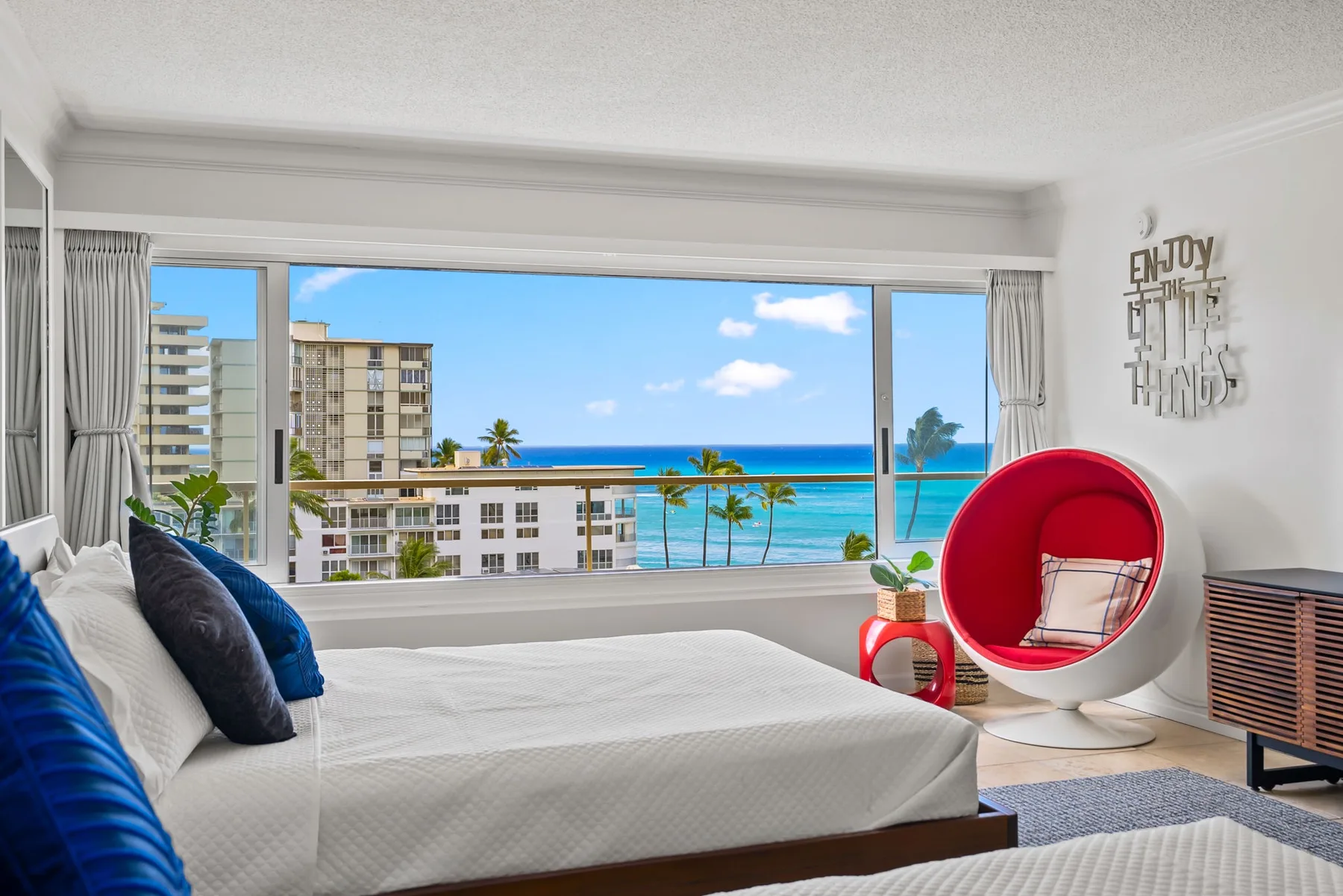 Un dormitorio con una cama frente a una amplia ventana con vistas al mar.