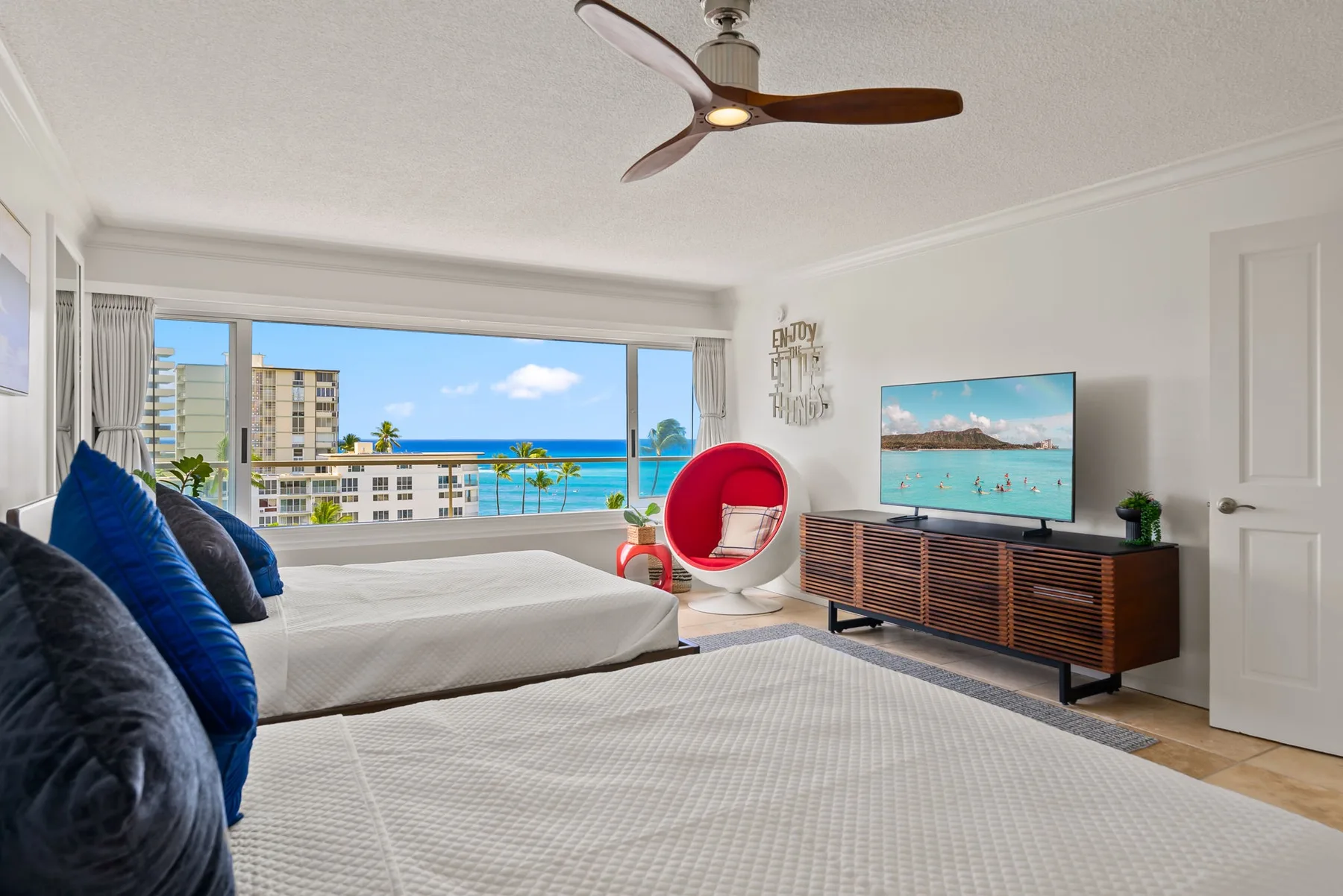 Un dormitorio luminoso con una cama grande y amplias ventanas con vistas al océano.