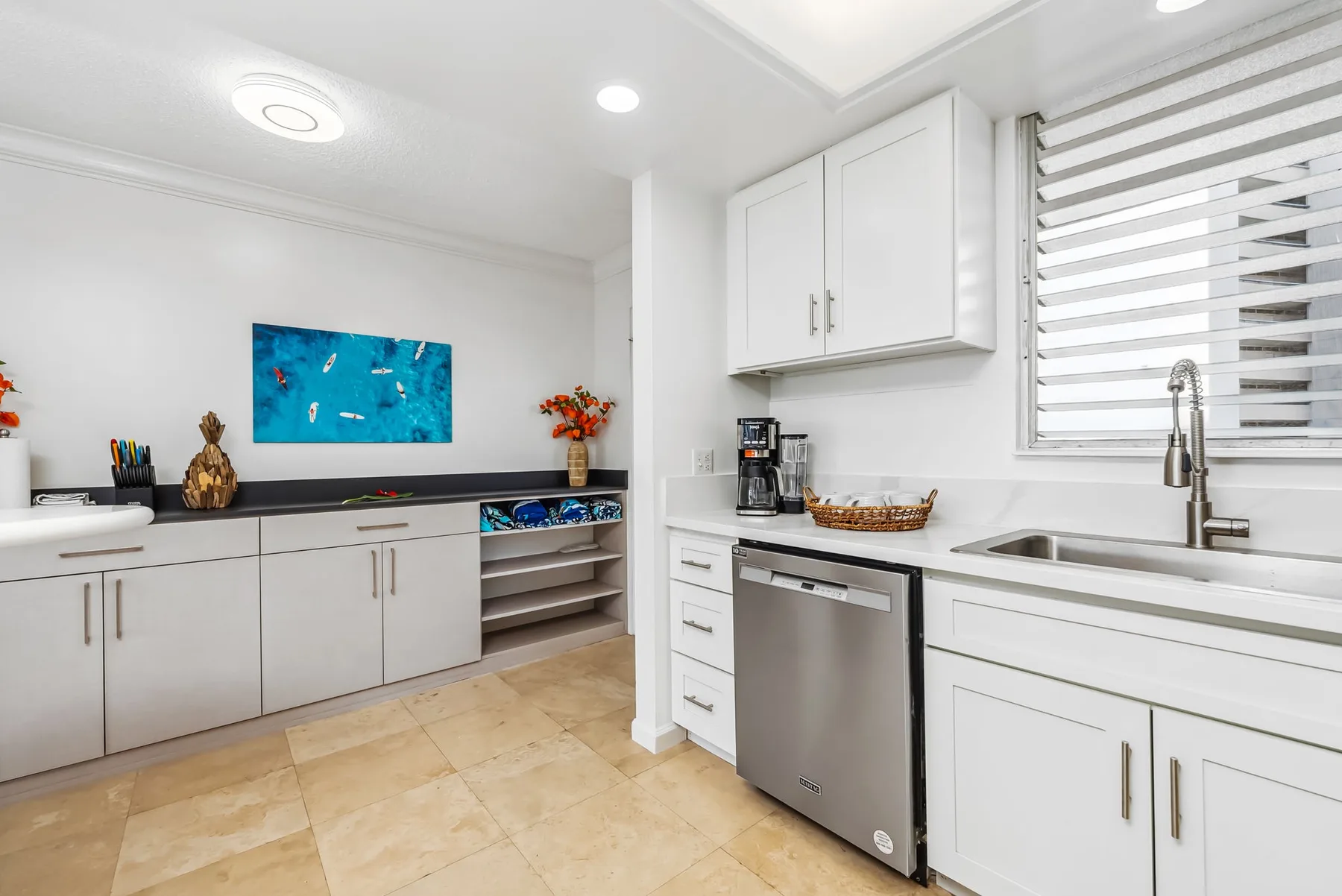 Una cocina luminosa con gabinetes blancos, una encimera y un fregadero.
