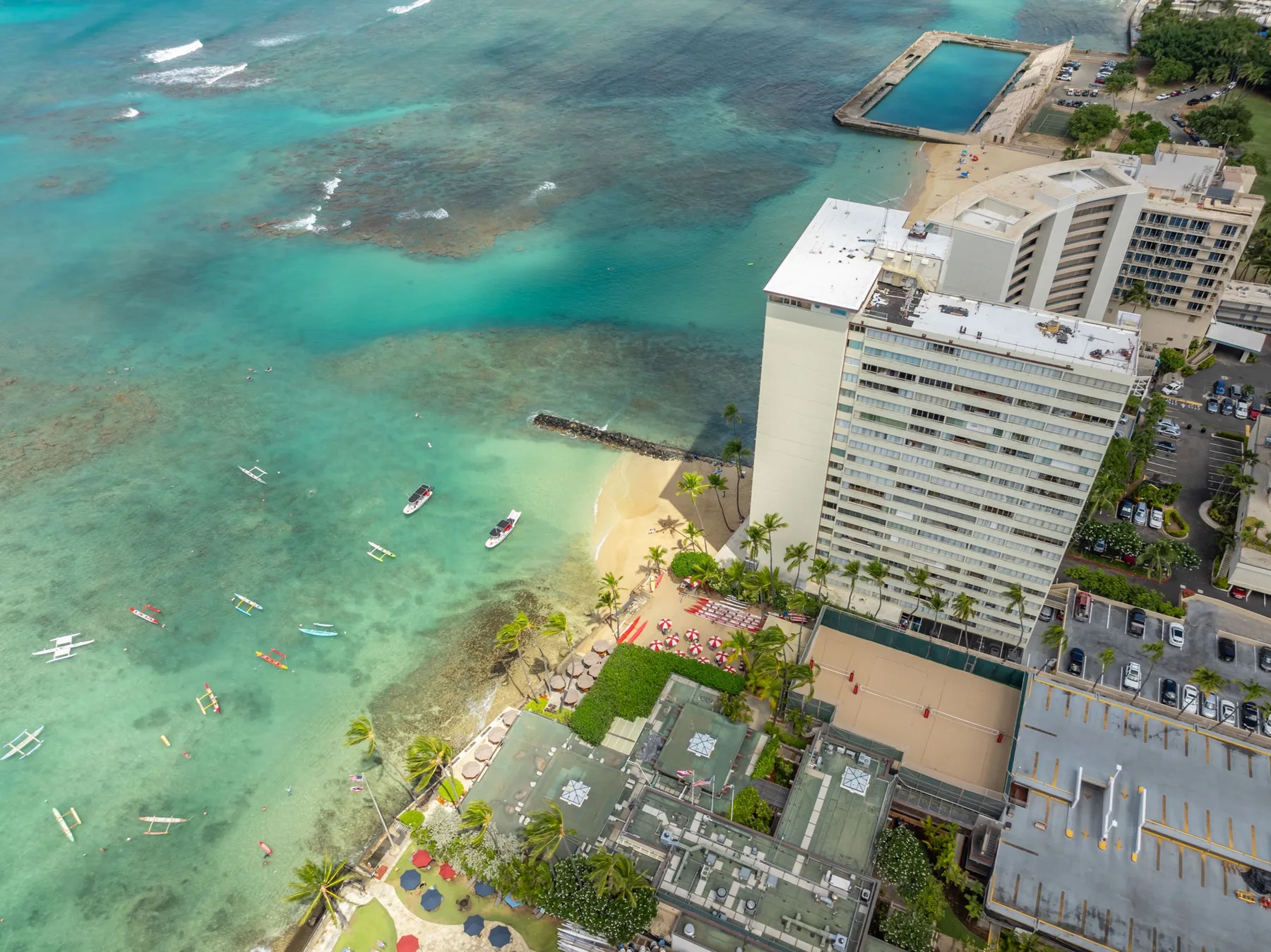 Vista aérea de un hotel junto a la playa, con agua turquesa y arena.