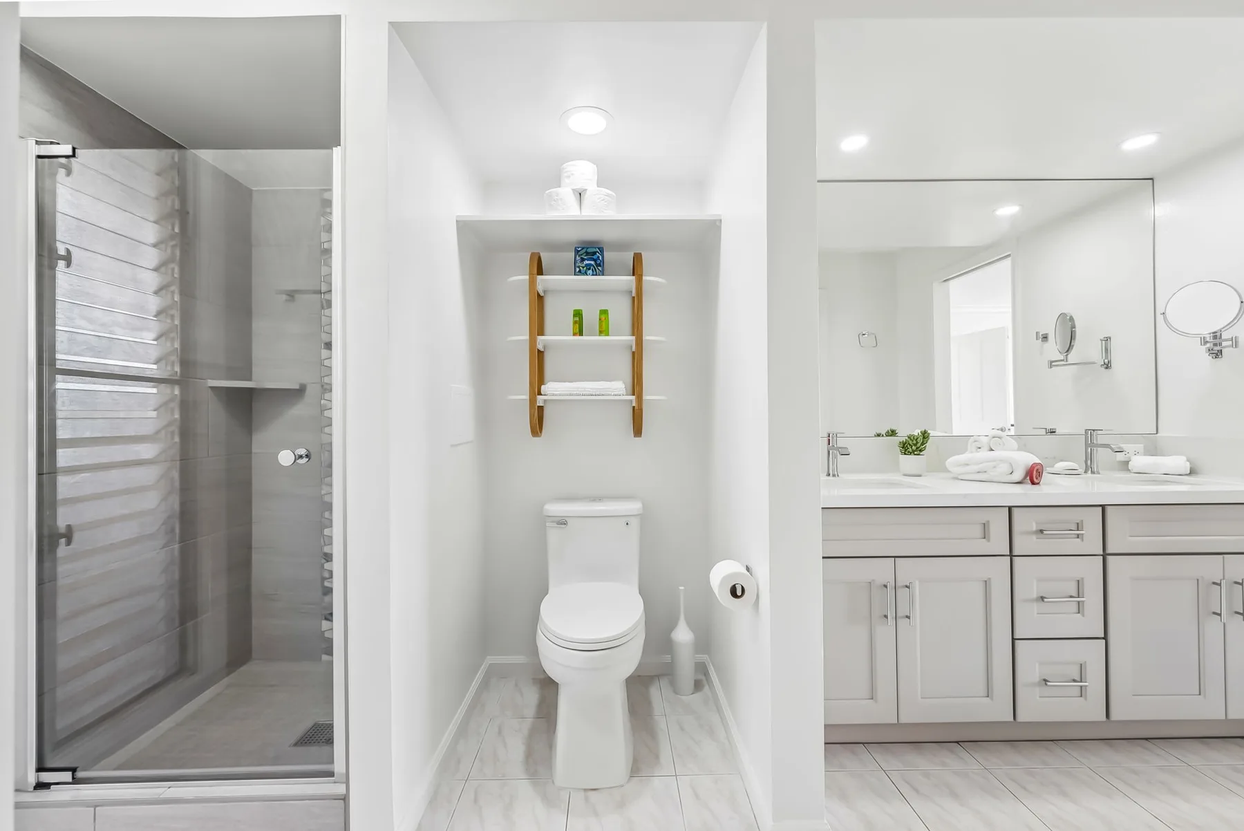 Un baño luminoso con ducha de vidrio, inodoro y lavabo.