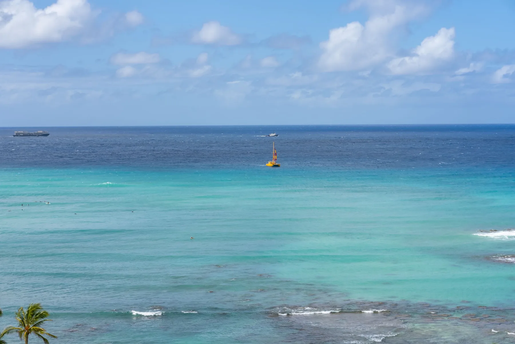El océano azul se extiende bajo un cielo parcialmente nublado, con una pequeña embarcación mar adentro.