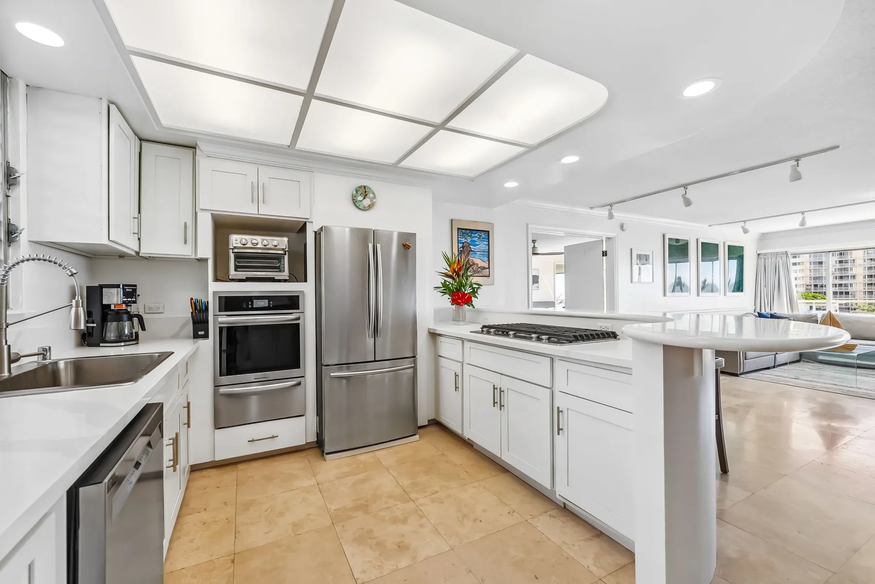 Una cocina blanca y luminosa con electrodomésticos de acero inoxidable y una isla grande.