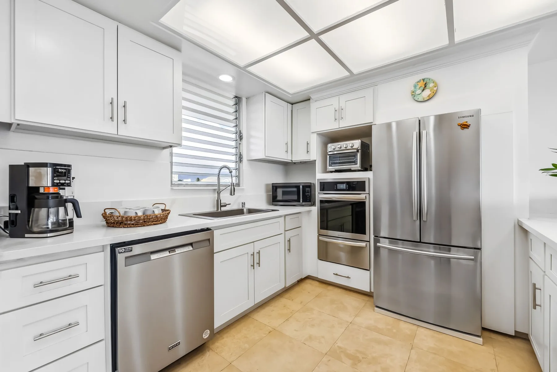 Una cocina luminosa con gabinetes blancos, electrodomésticos de acero inoxidable y una ventana.