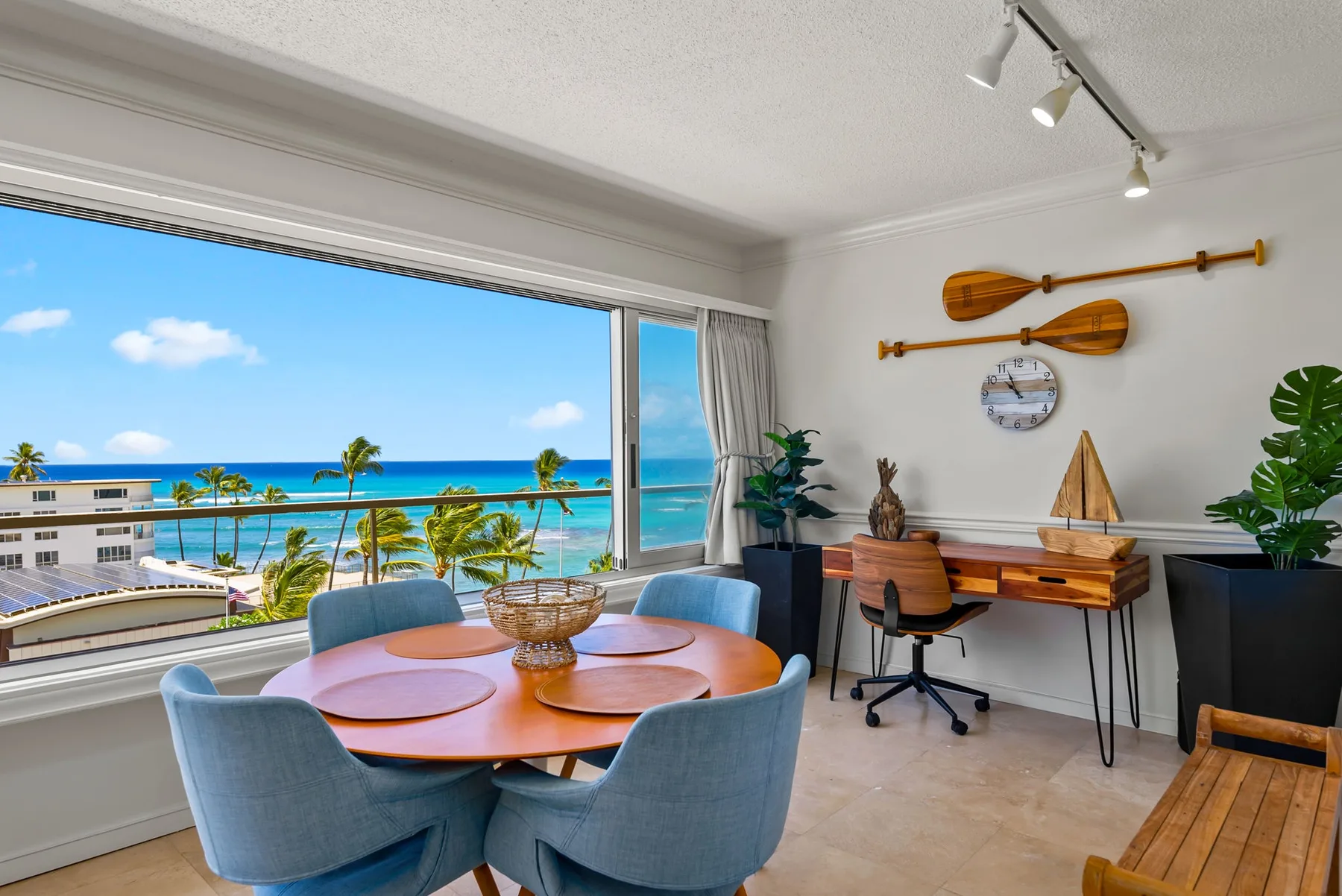 Un comedor con una mesa redonda junto a una ventana grande con vista al mar.
