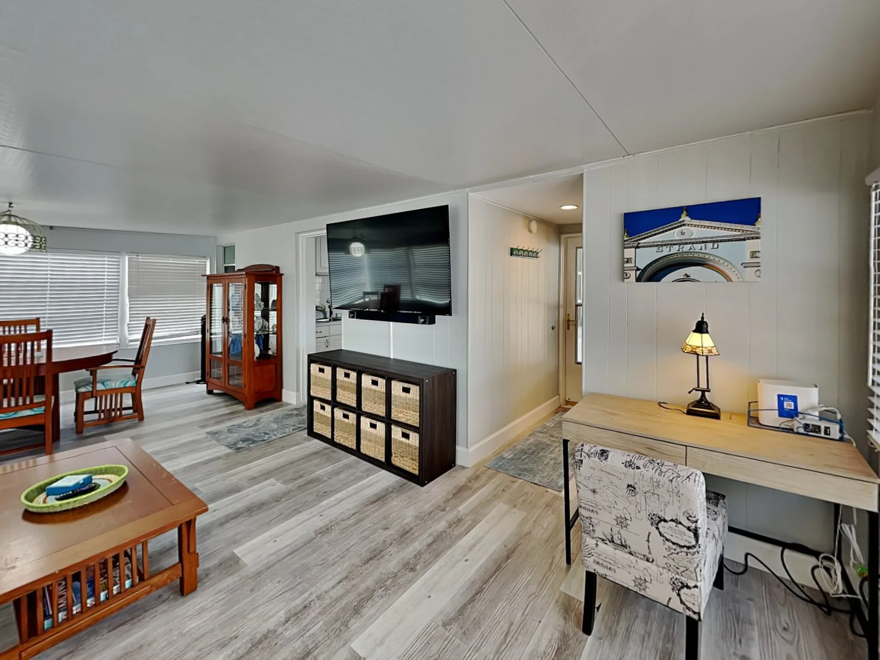 Sala de estar y comedor con televisor, mesa de madera y escritorio.
