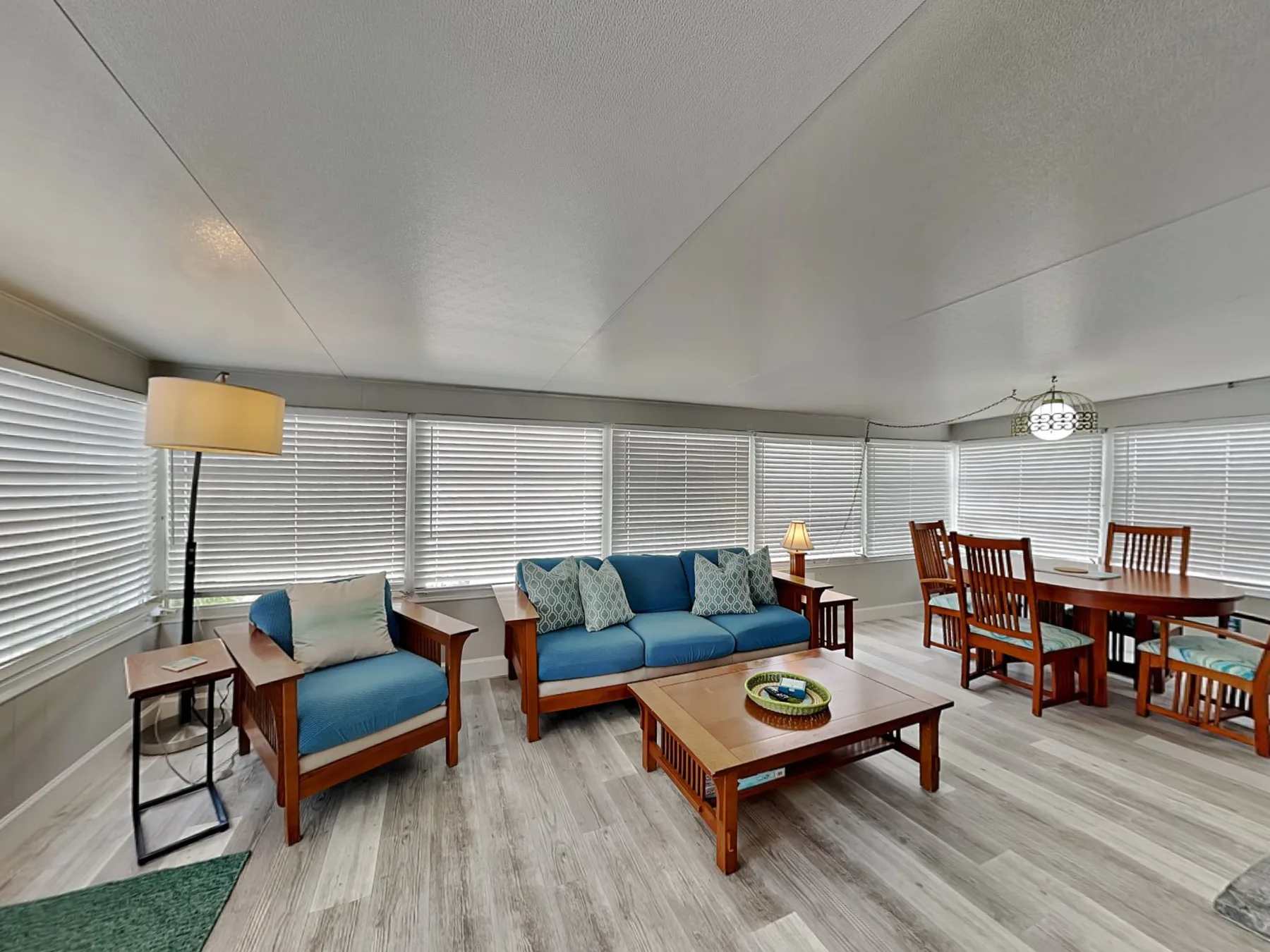 A bright living room with blue seating, a coffee table, and wide windows.