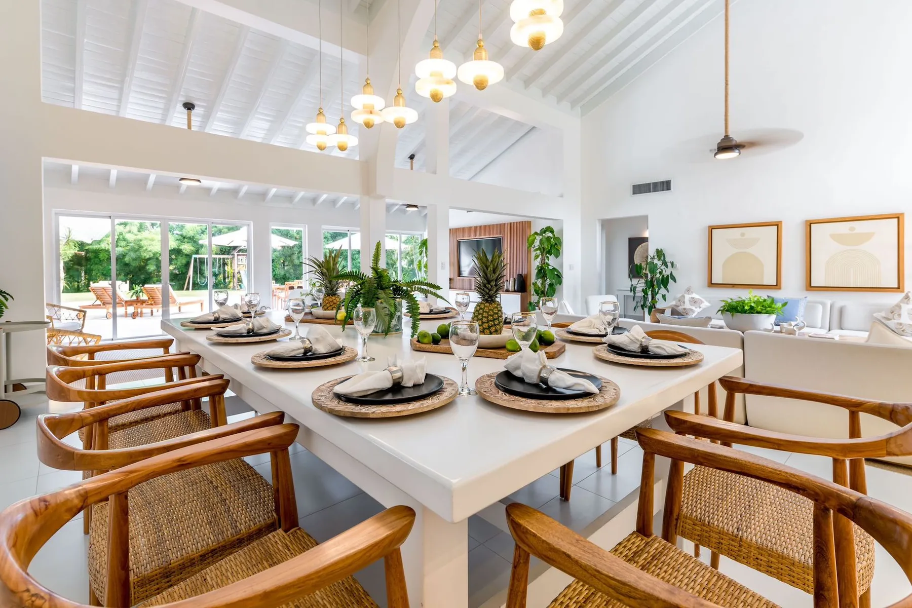 A bright dining room with a long table set beneath hanging lights.