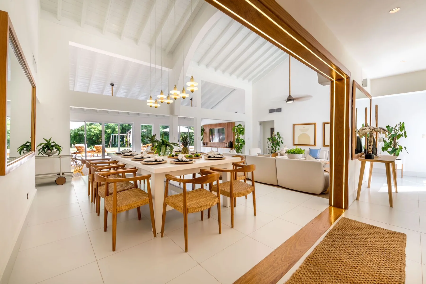 A bright open-plan dining and living area with a long dining table and seating.