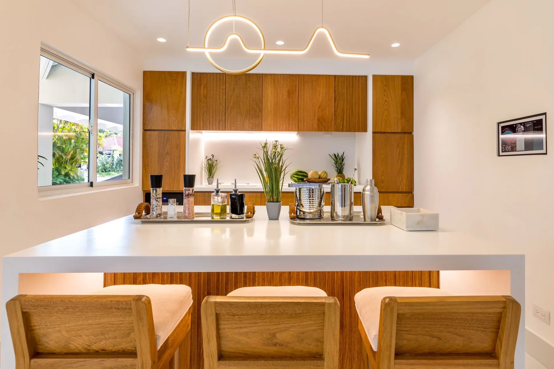 A bright kitchen with a wide white island and wooden cabinetry.