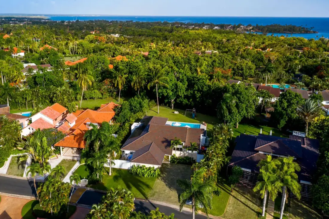 Aerial view of homes among lush greenery, with the coastline visible in the distance.