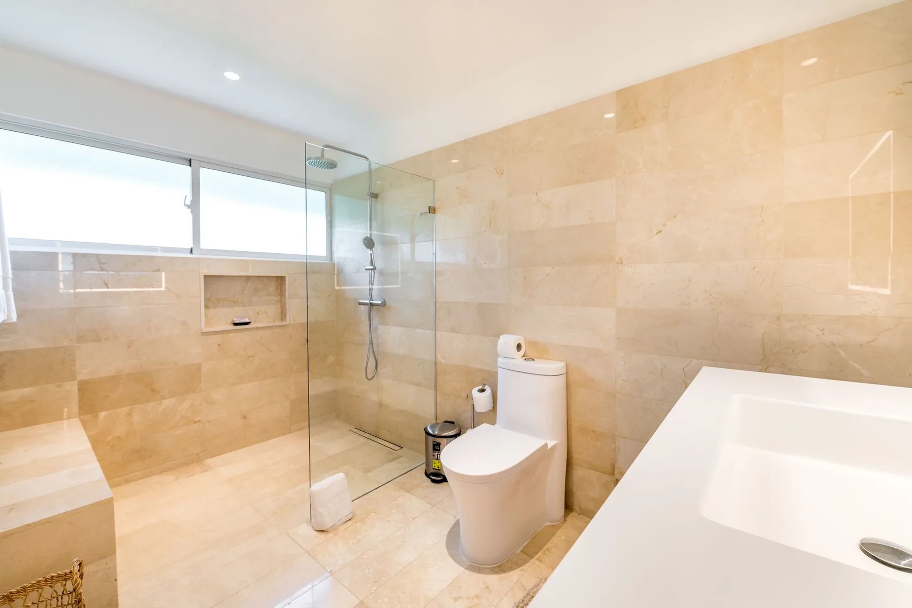 A bright tiled bathroom with a shower, toilet, and bathtub.