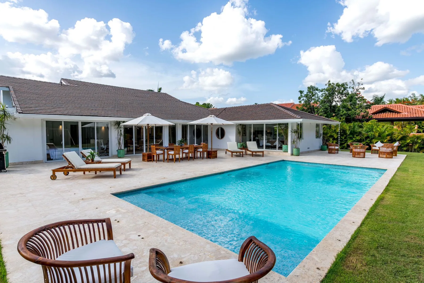 A patio surrounds a swimming pool in front of a single-story house.