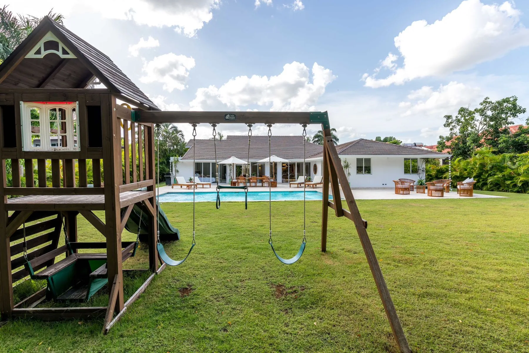 A grassy outdoor play area with a wooden swing set and play structure.