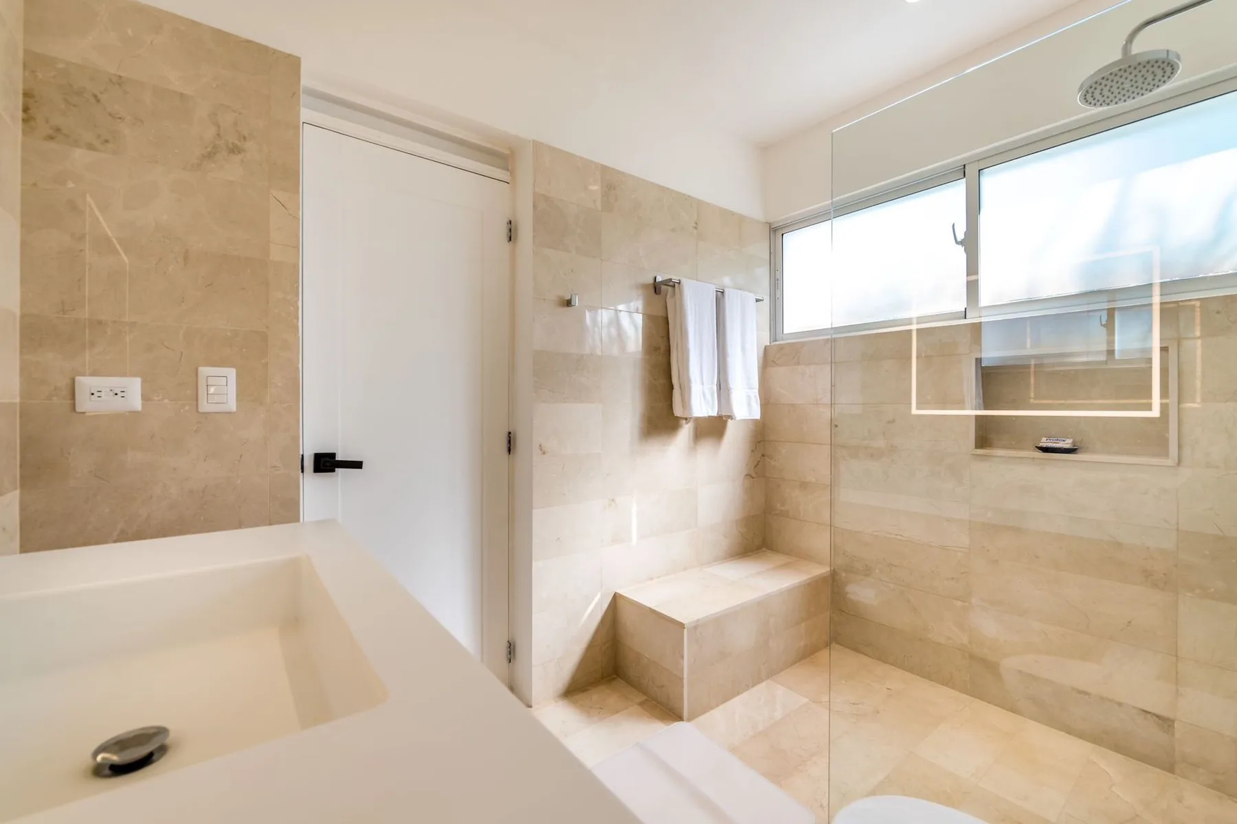 A bright tiled bathroom with a bathtub and walk-in shower.