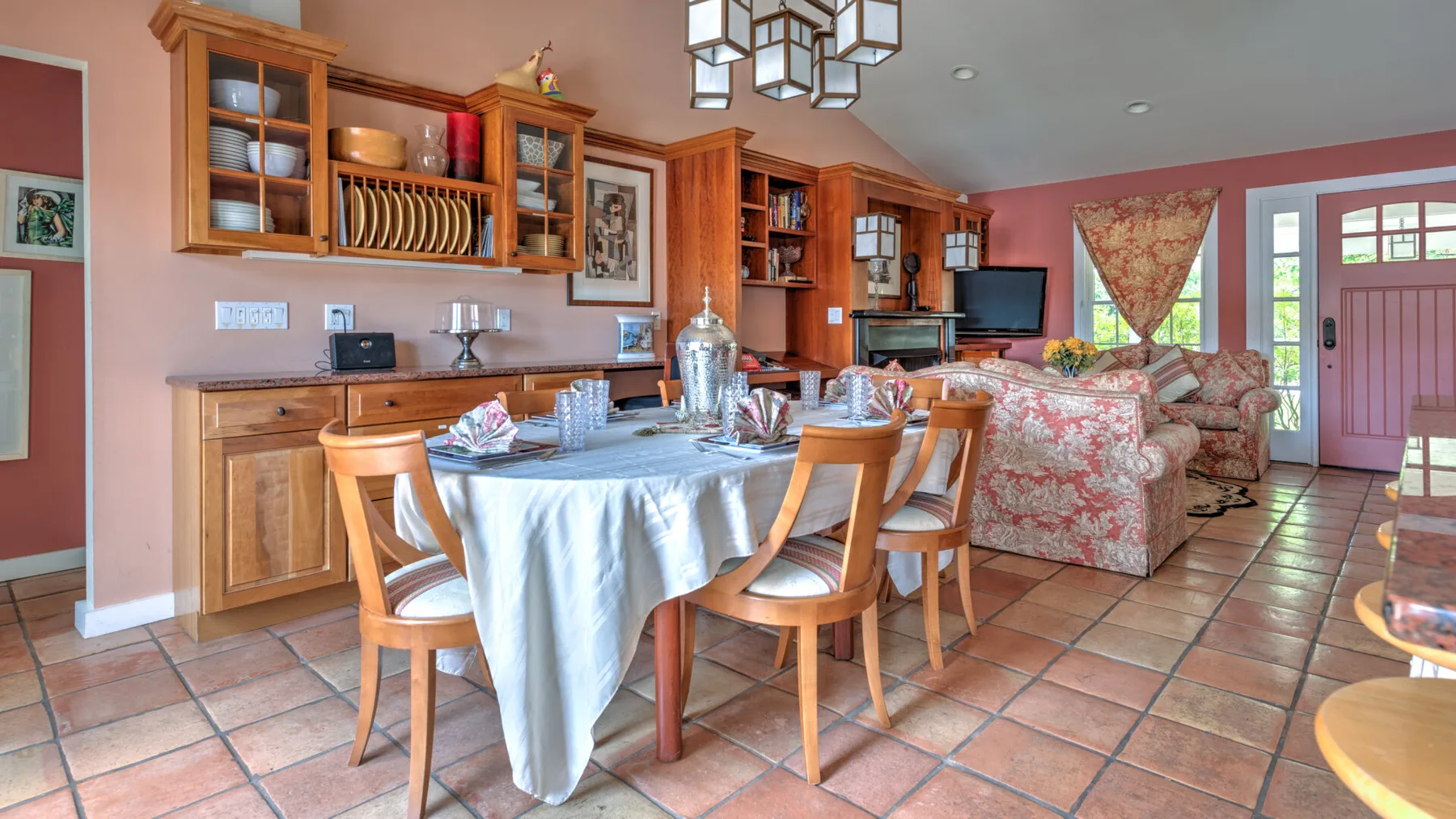 Comedor con una mesa y sillas junto a armarios de madera y un televisor.