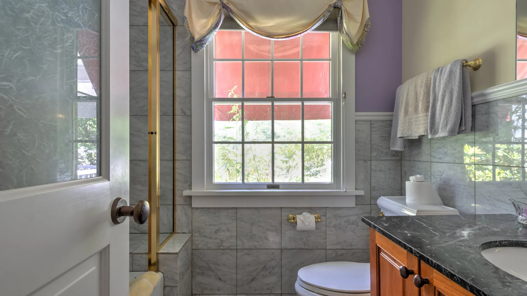 Un baño con ventana, ducha, inodoro y tocador.