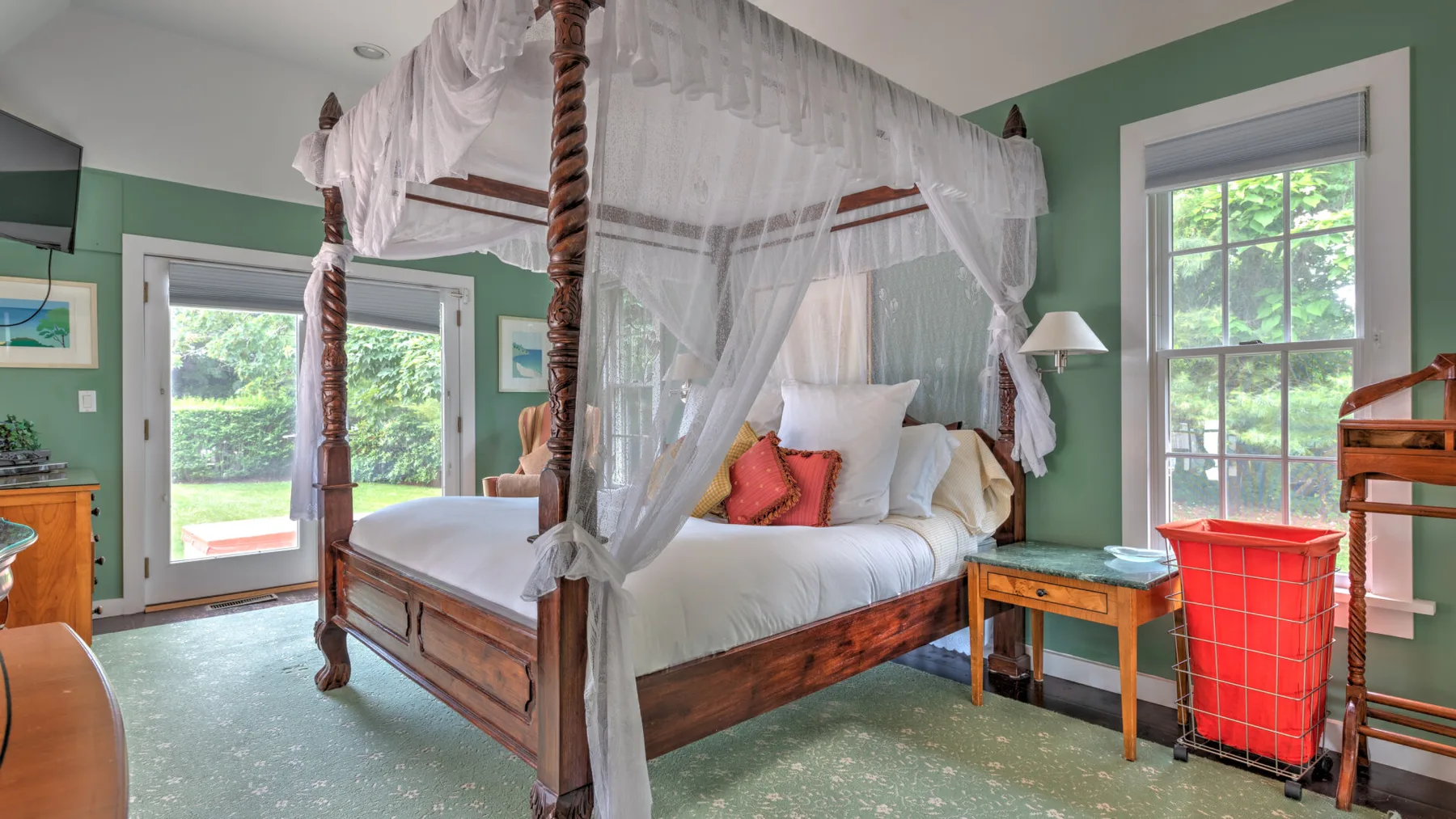 Un dormitorio con una cama con dosel de madera y paredes verdes.