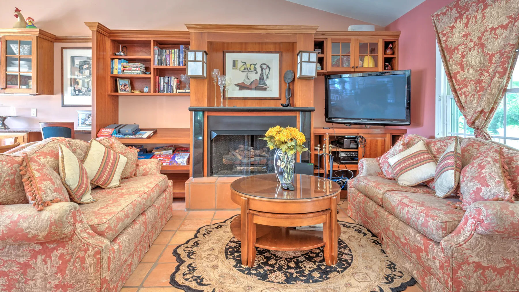 Una sala de estar con asientos estampados, una mesa de centro de madera y estanterías empotradas.