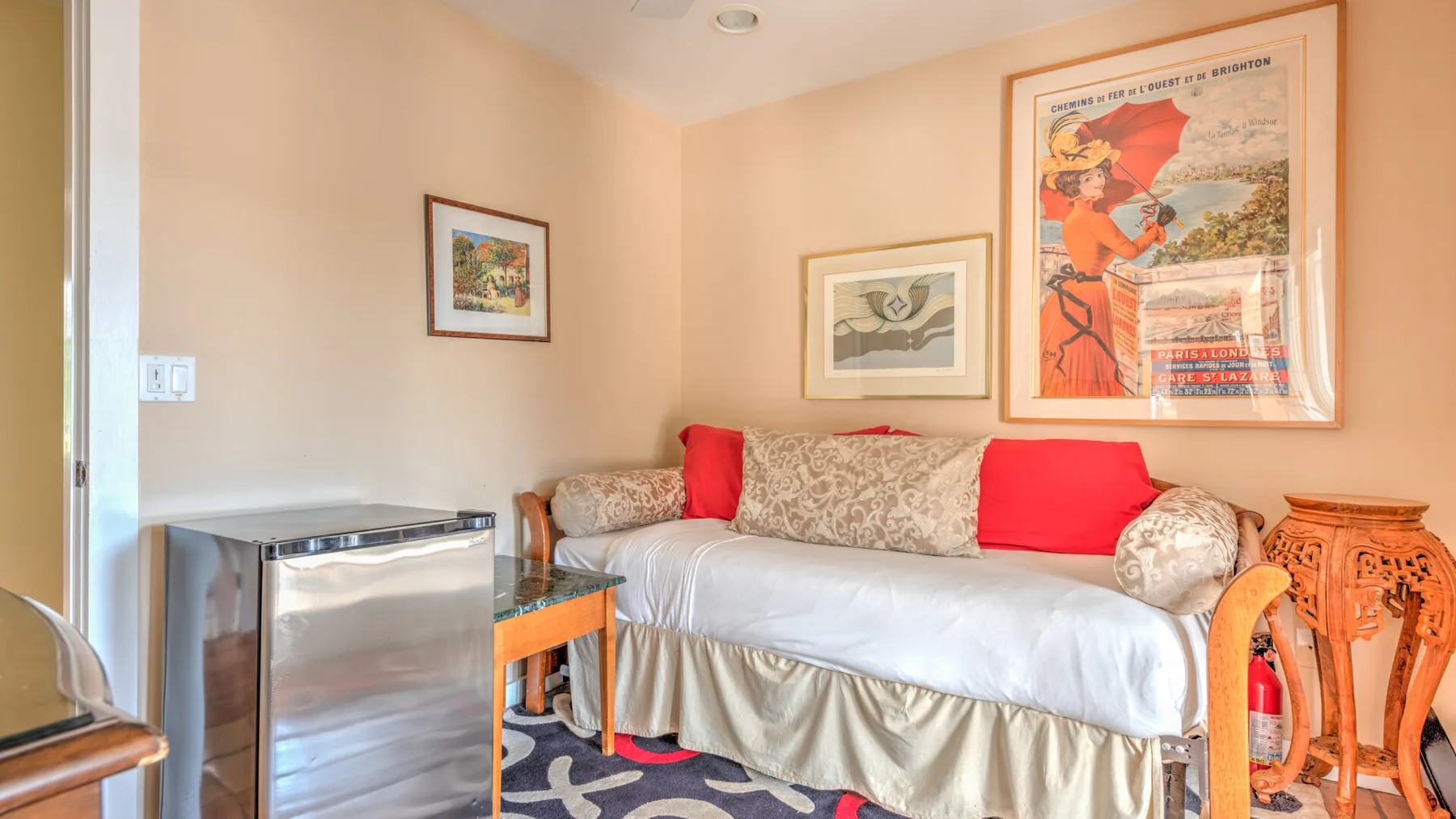 Una zona de estar con sofá, cuadros enmarcados y una pequeña mesa de madera.