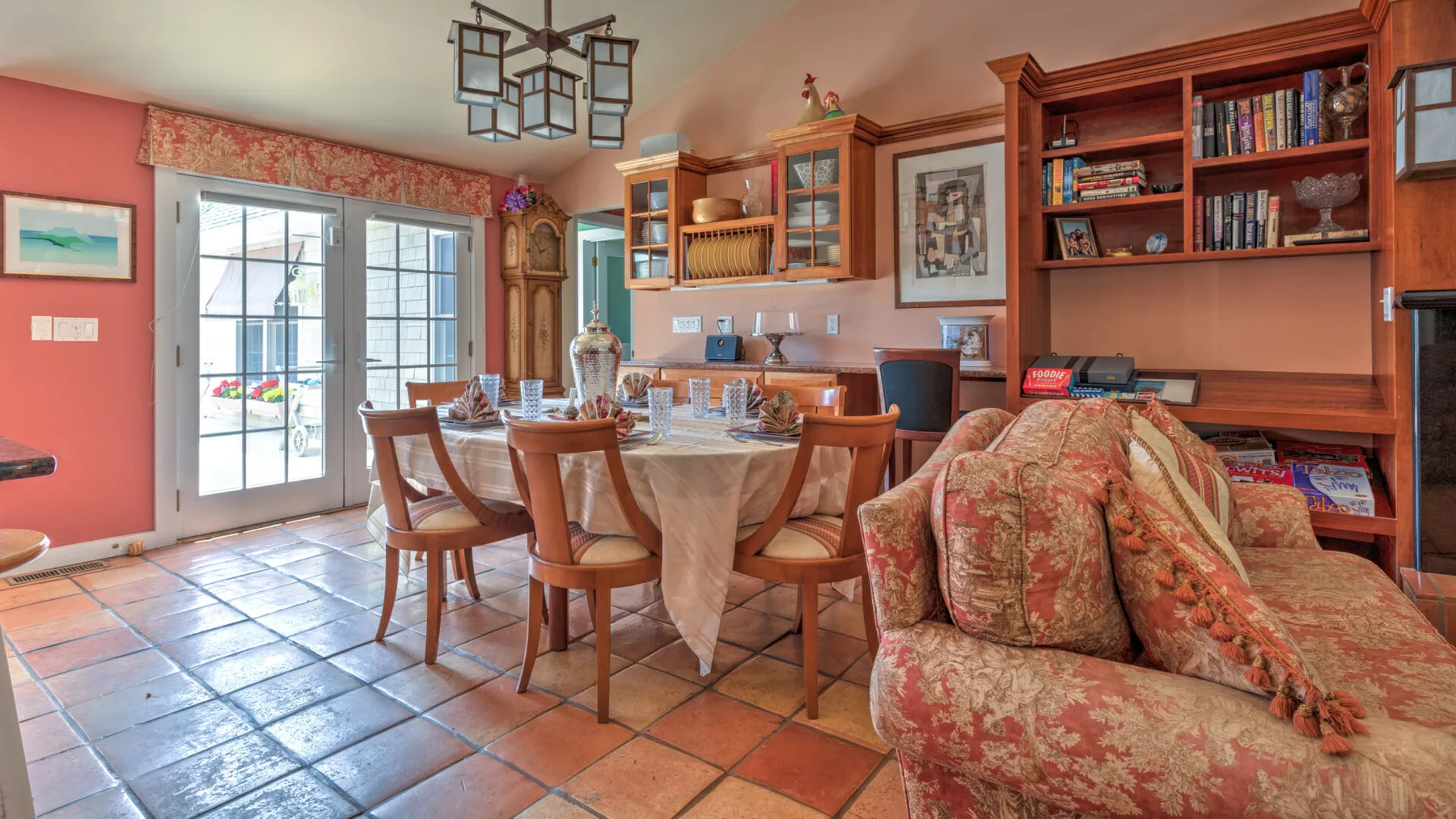 Un comedor con una mesa puesta, asientos de madera y estanterías empotradas.