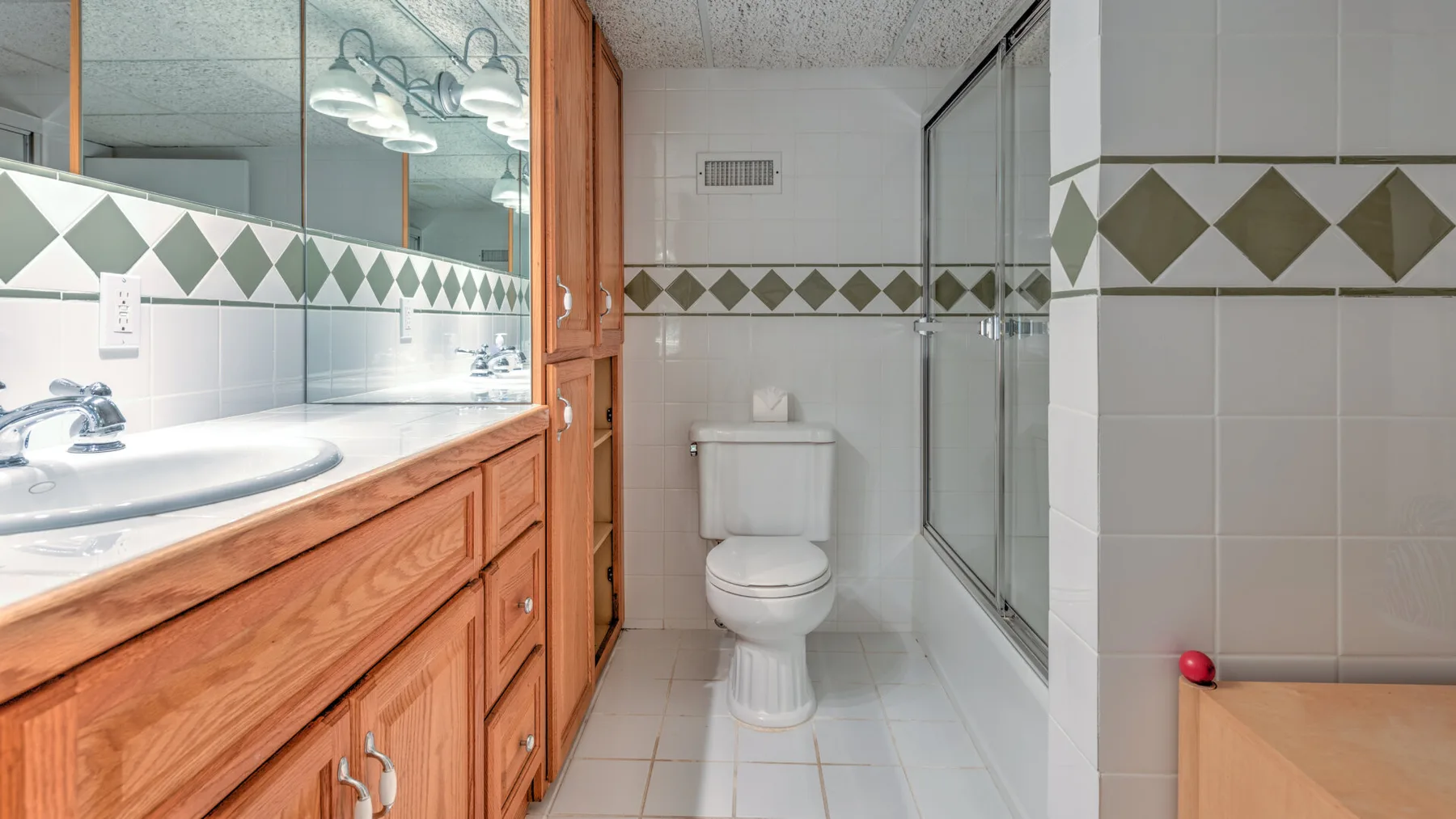 Un baño con azulejos, inodoro, ducha de vidrio y lavabo de madera.