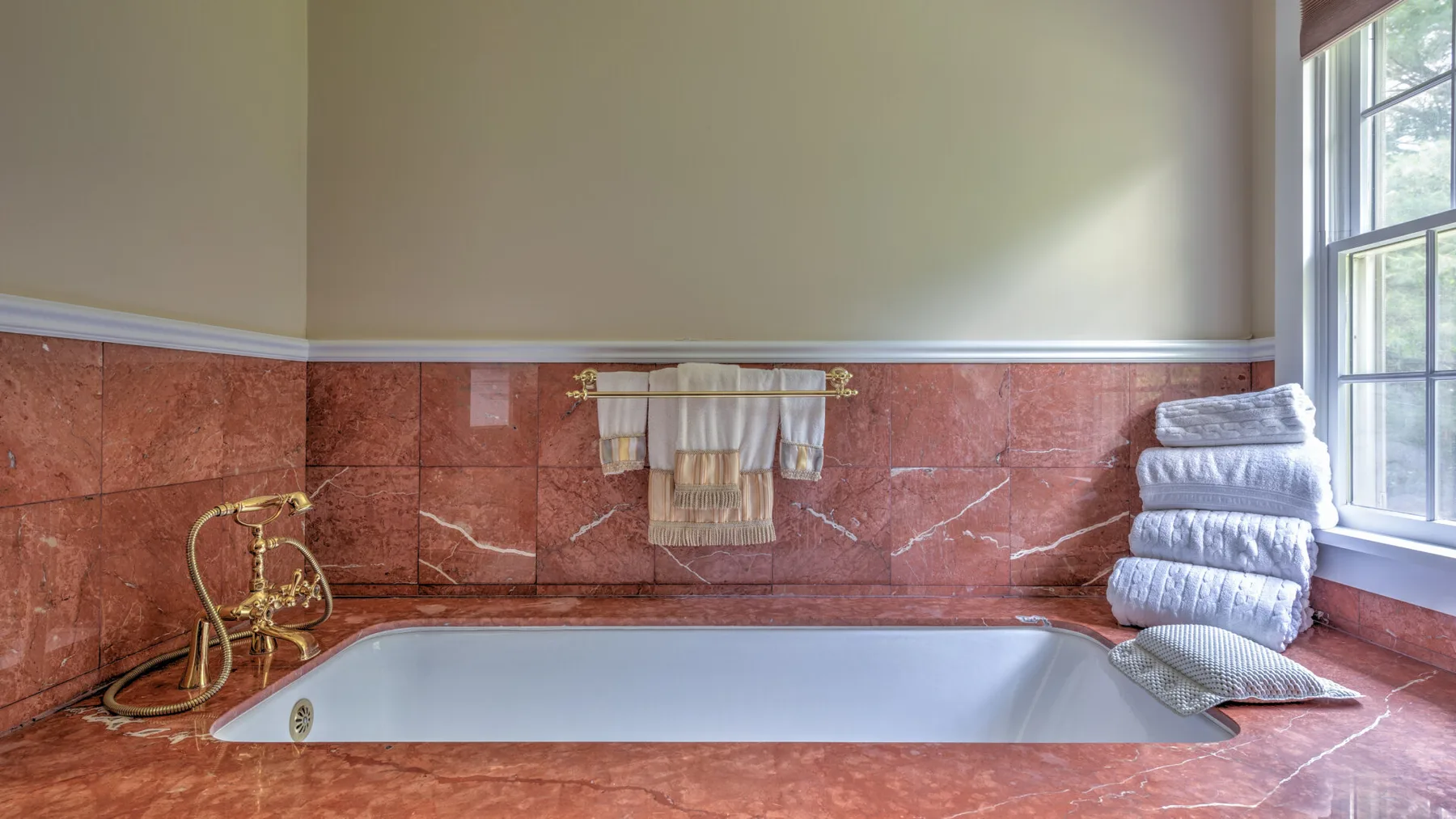 Un baño con una bañera empotrada, paredes revestidas de azulejos y una ventana.
