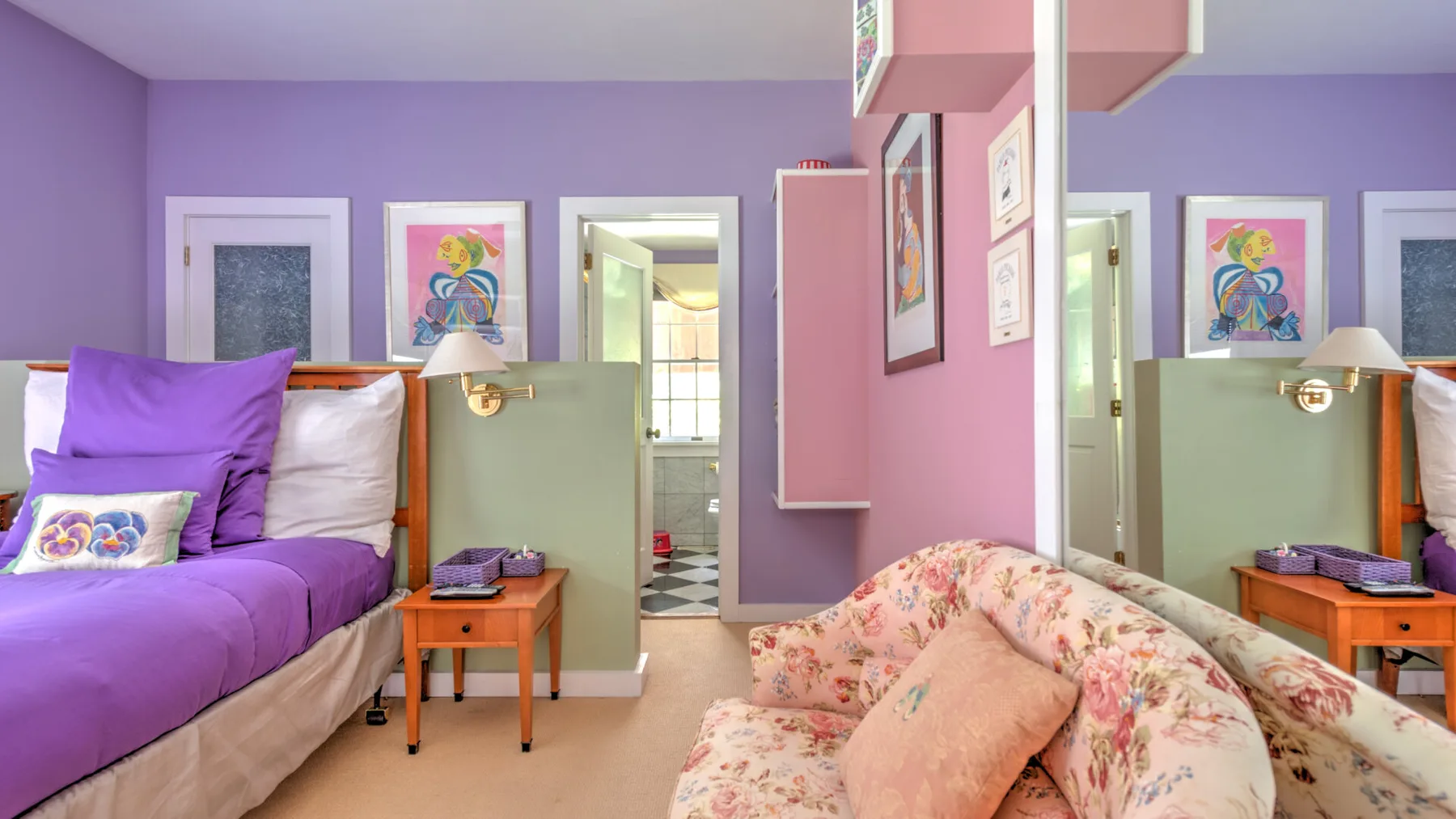 Un dormitorio colorido con una cama, asientos florales y cuadros enmarcados.