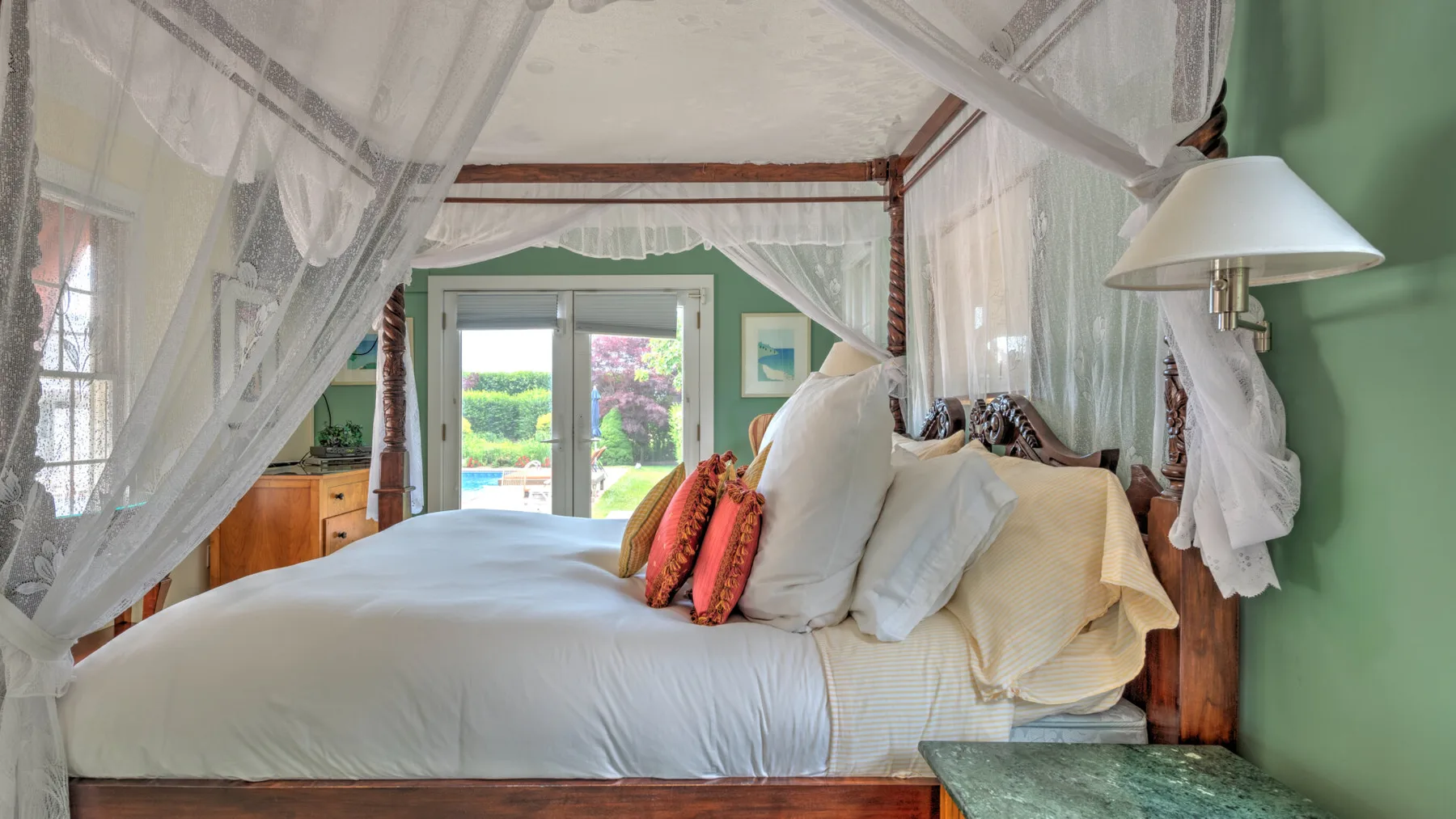 Un dormitorio con una cama grande vestida con ropa de cama blanca y cortinas transparentes.
