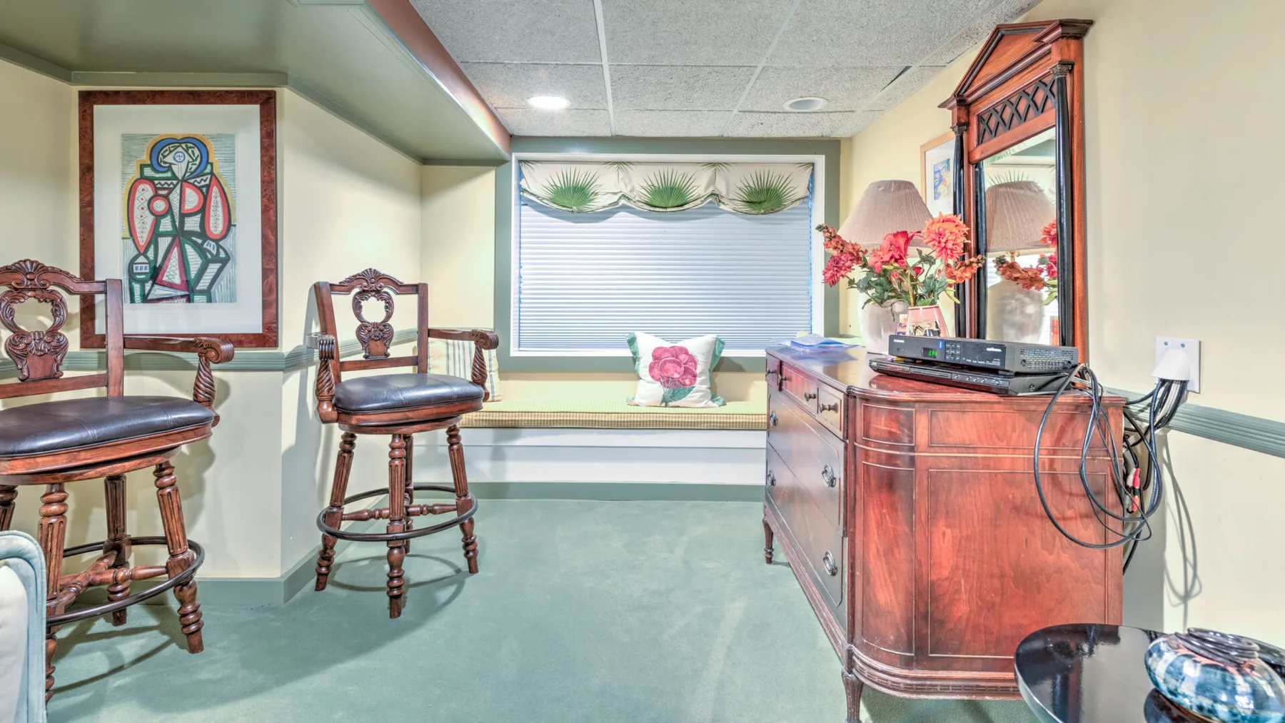 Una habitación amueblada en el sótano, con una ventana, asientos de bar y un mueble de madera.