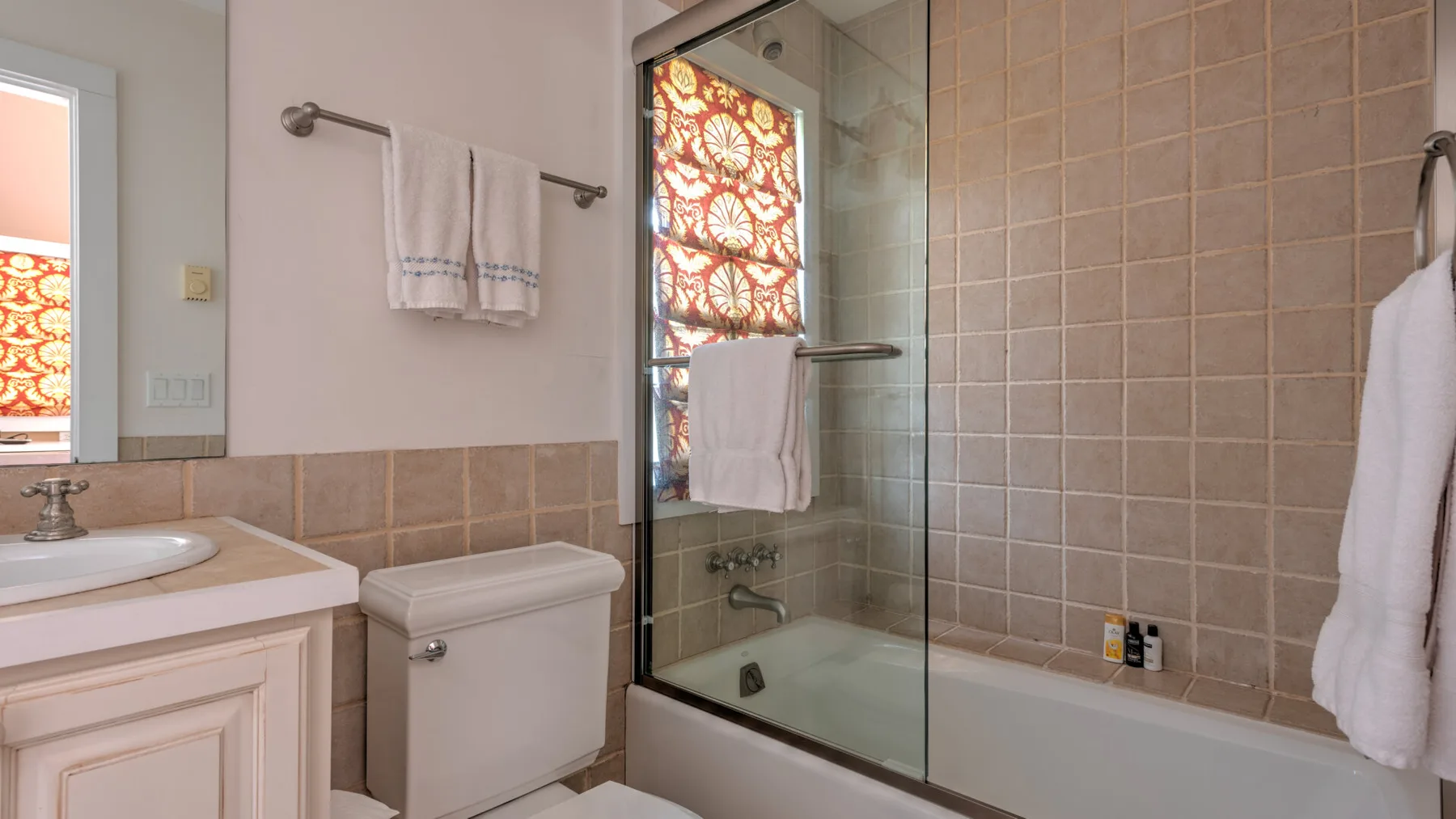 Un baño con lavabo, inodoro y ducha de vidrio junto a la bañera.