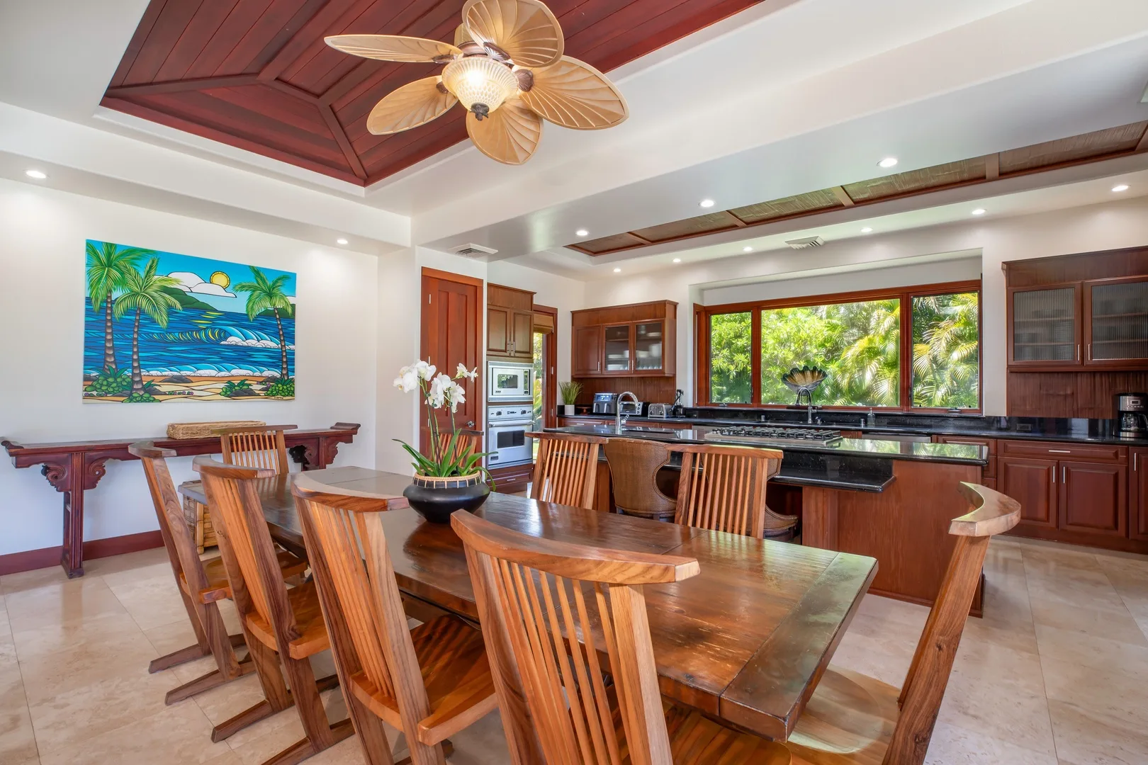 Una amplia cocina con comedor tiene una mesa de madera junto a la isla de cocina.