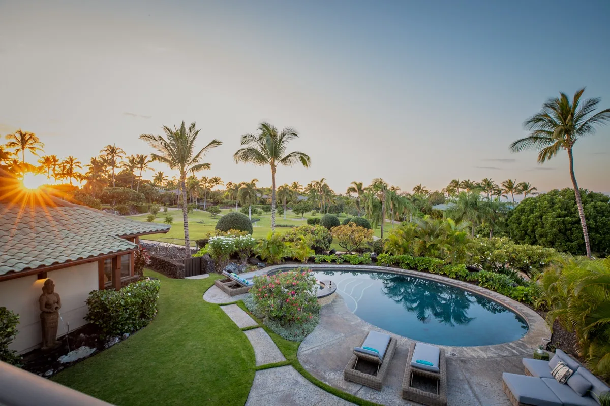 Una zona de piscina al aire libre rodeada de vegetación tropical.