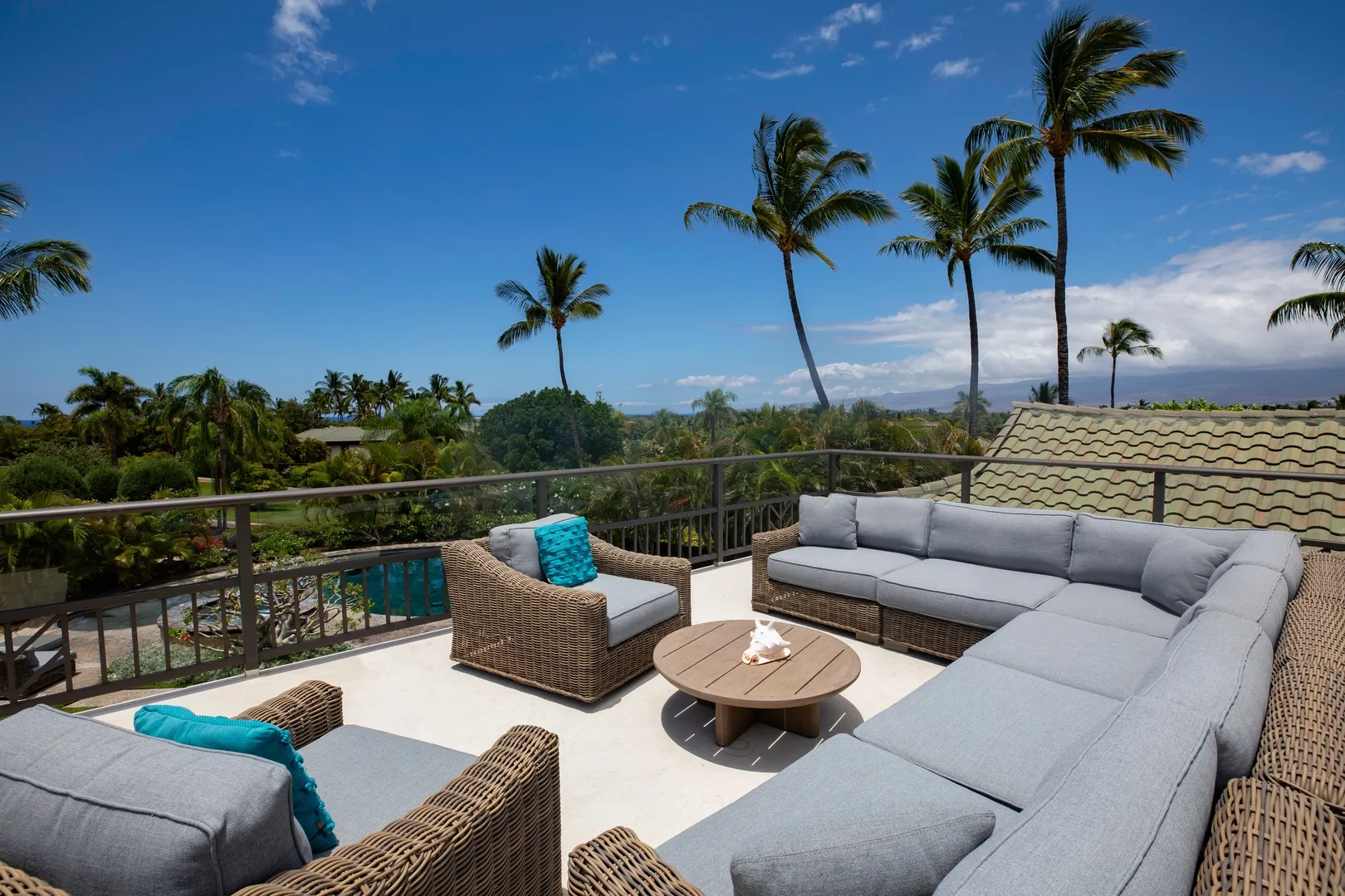 Una zona de estar al aire libre con muebles acolchados y palmeras al fondo.