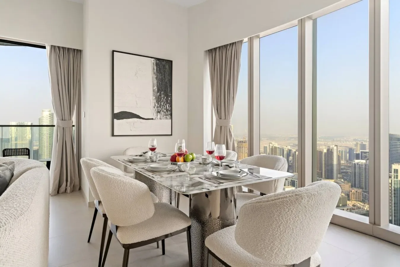 Comedor con una mesa y asientos tapizados junto a ventanales de piso a techo.