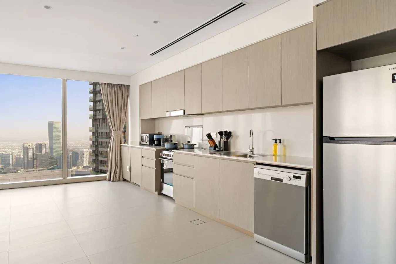 Una cocina moderna con armarios claros y una gran ventana con vistas a la ciudad.