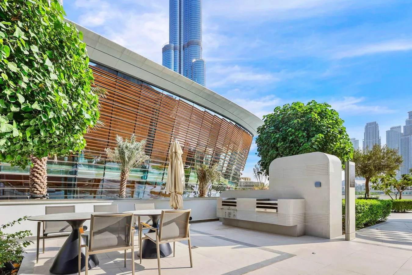 Una terraza exterior con asientos, jardineras y un edificio moderno curvo.