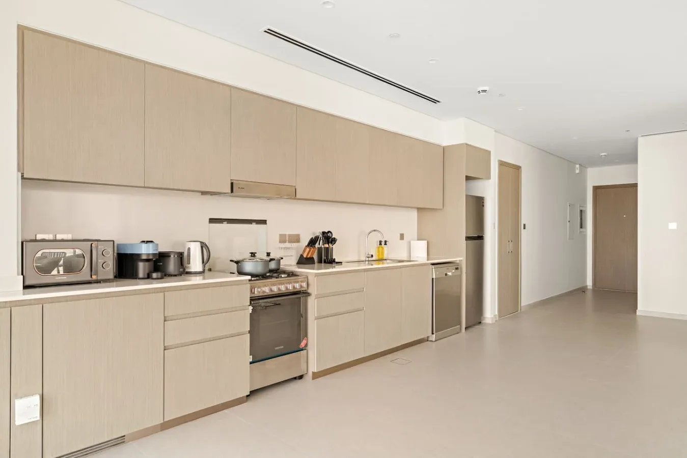 Una cocina moderna con gabinetes claros, una encimera y electrodomésticos integrados.