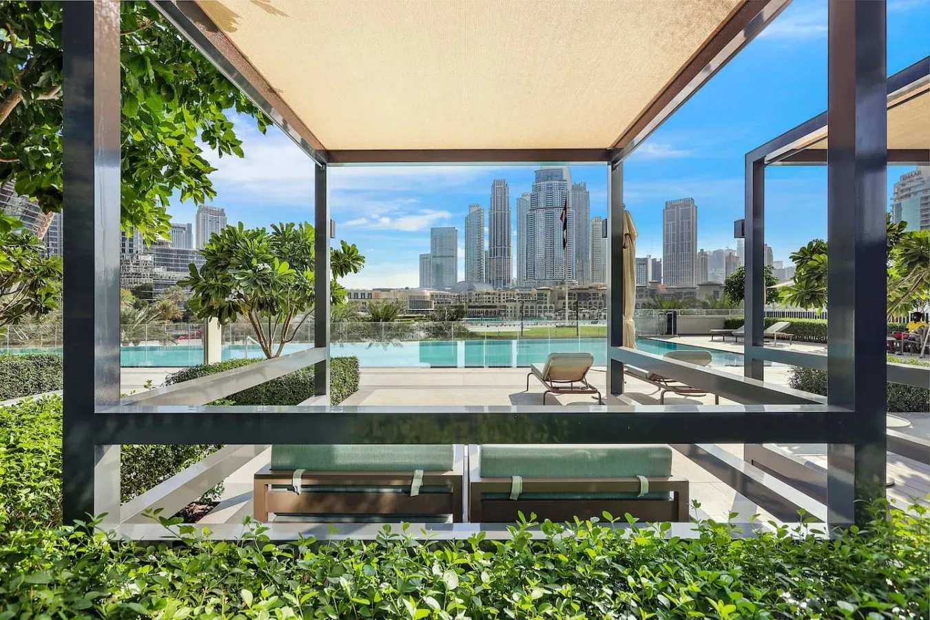 Una zona de estar al aire libre cubierta da a una piscina y al perfil urbano.
