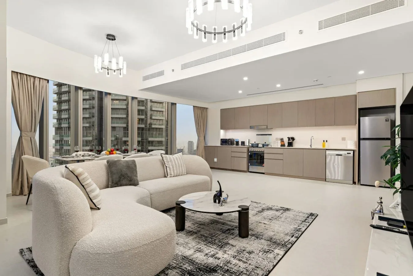 Una luminosa sala de estar y cocina de concepto abierto, con grandes ventanales y muebles de tonos neutros.