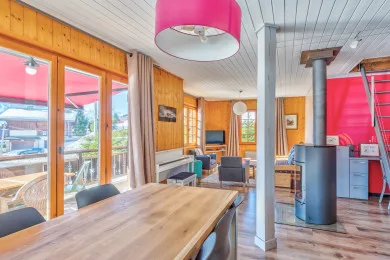 A wood-paneled dining area with a long table beside large windows.