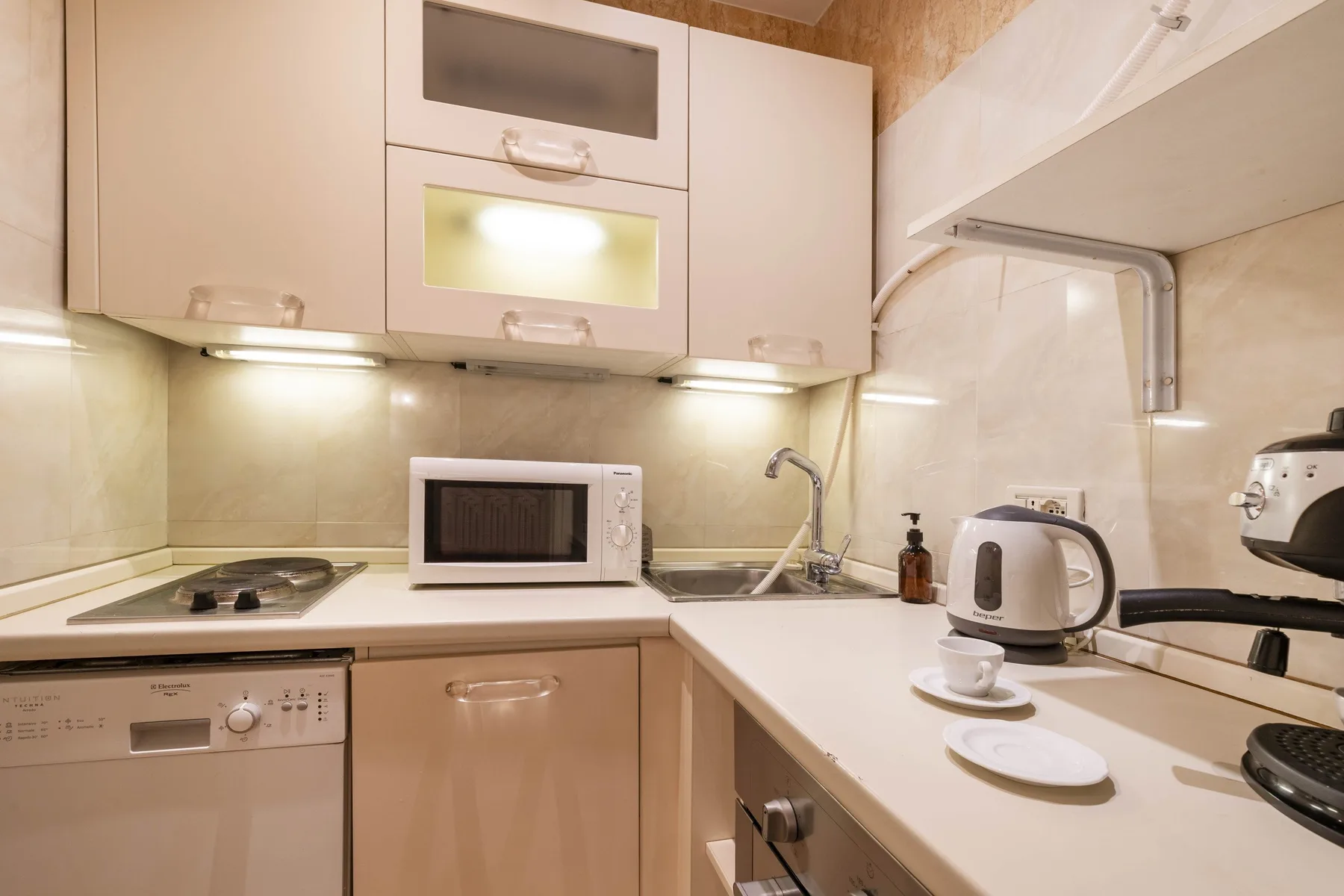 A compact kitchen with a countertop, sink, and built-in cabinets.
