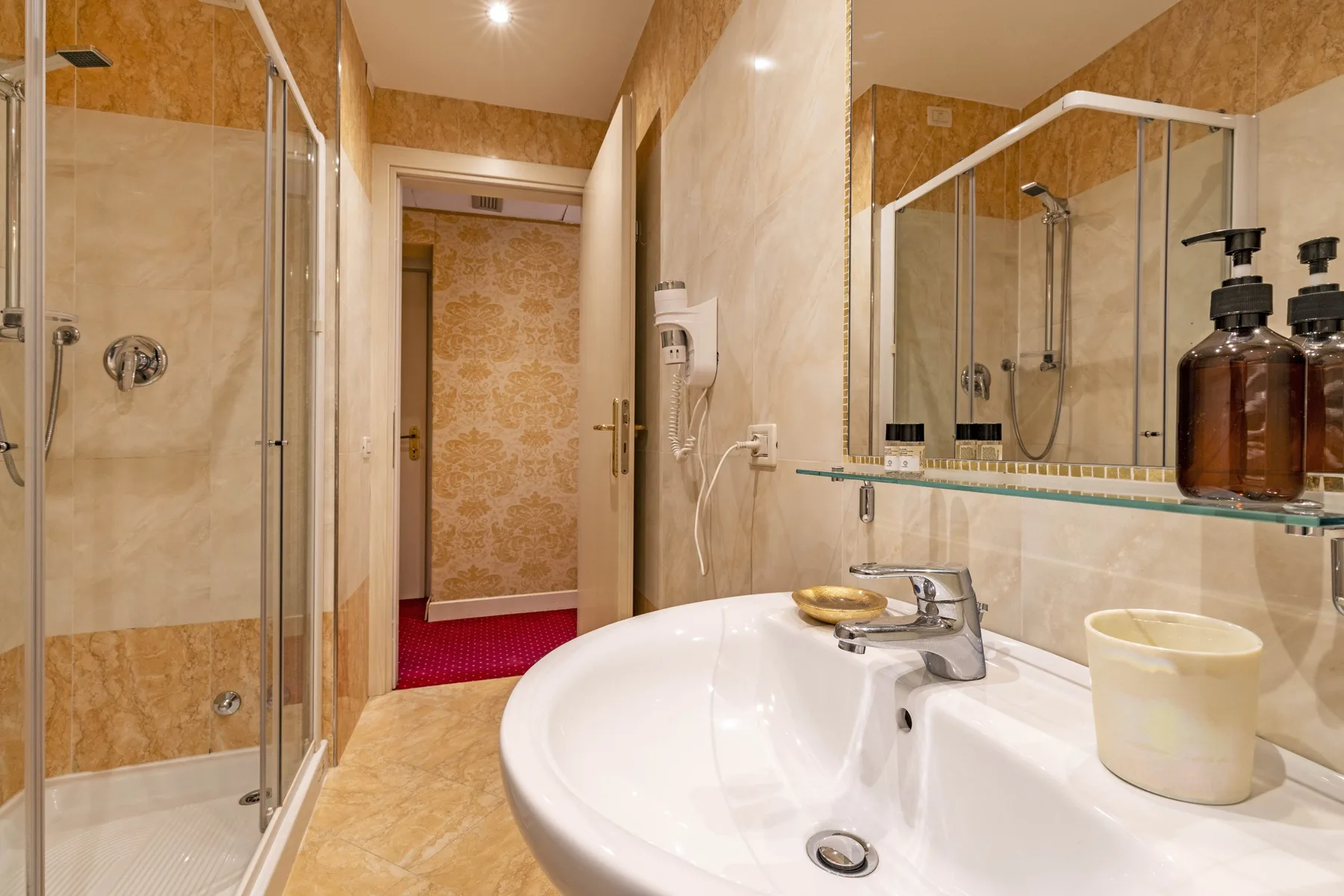 A bathroom with a curved sink, mirrored wall, and glass shower.