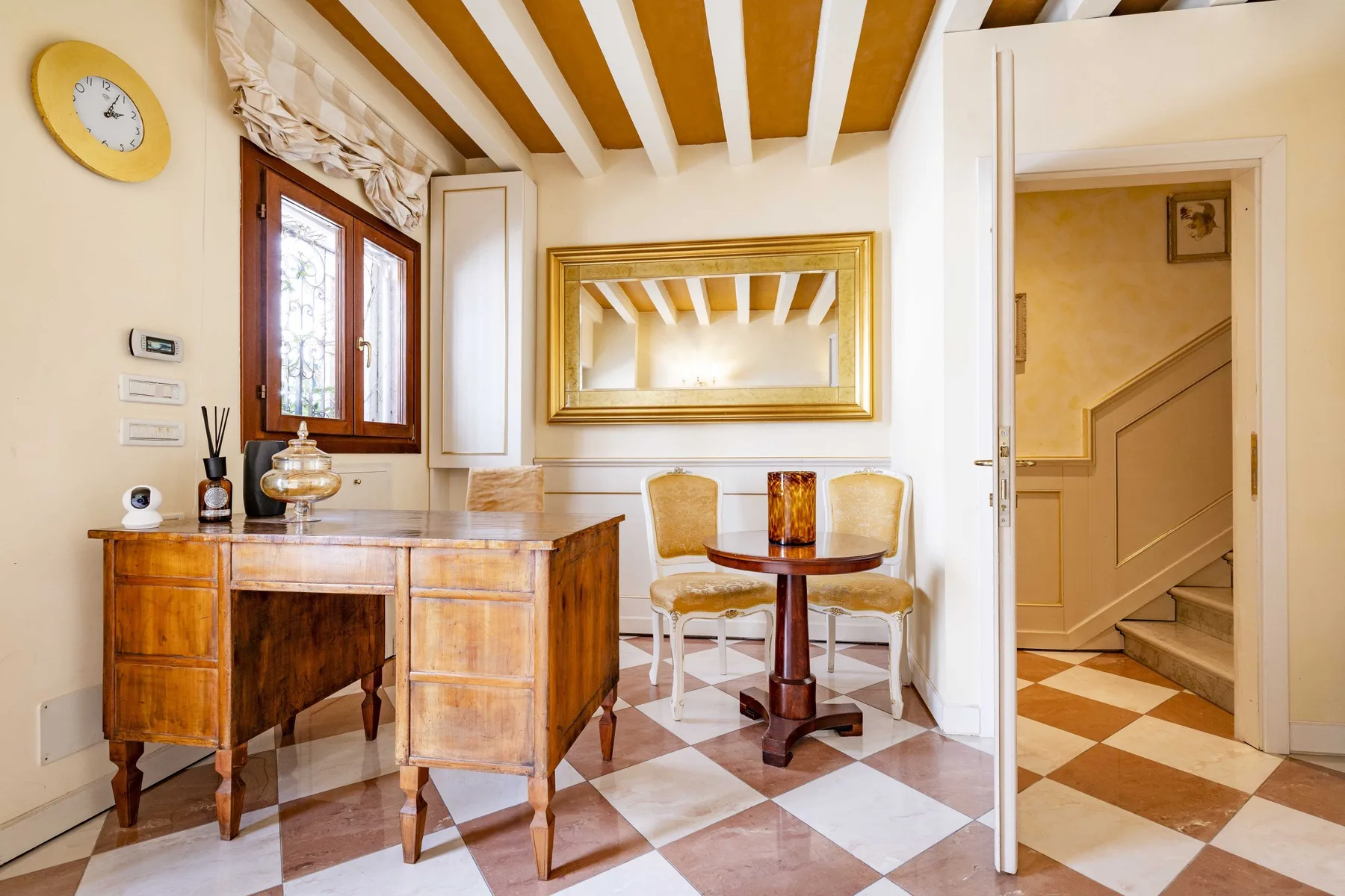 A furnished room with a wooden desk, small table, and patterned tile floor.