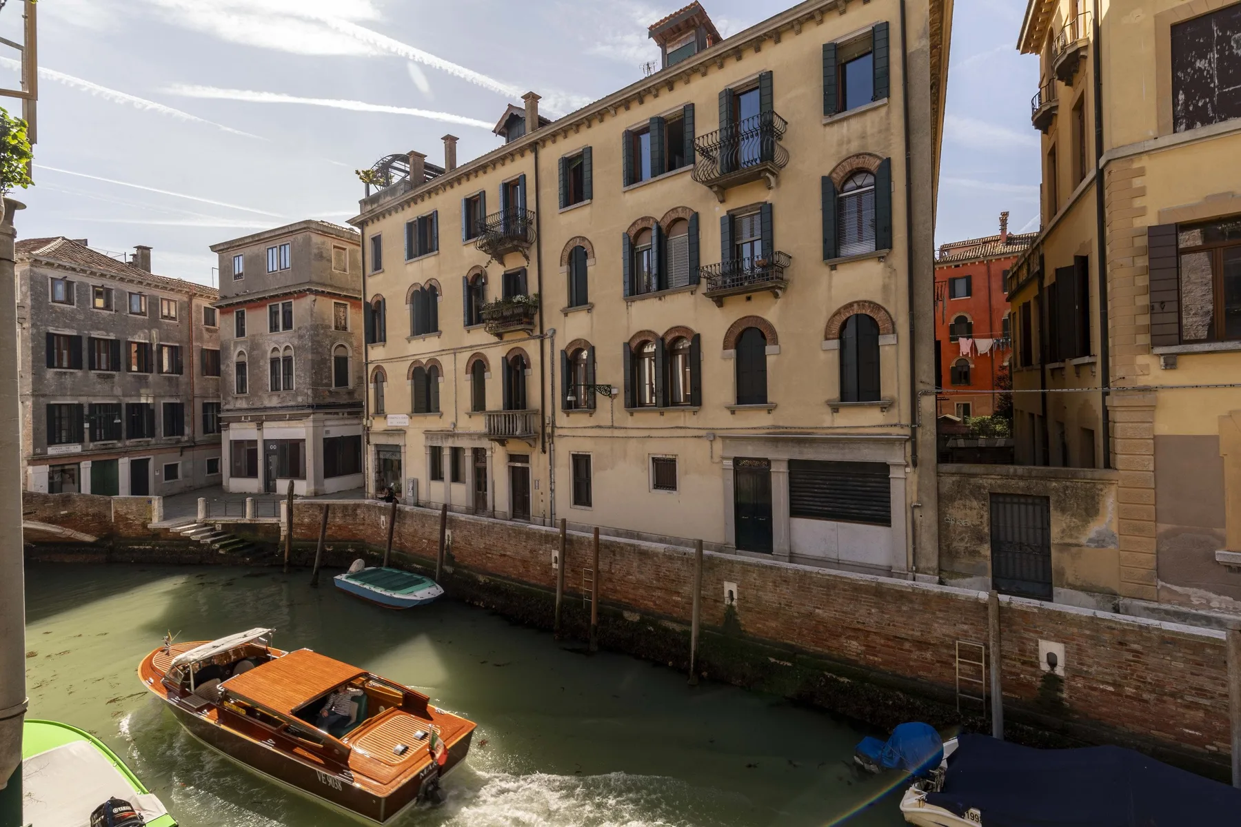 A canal runs between historic buildings, with a wooden boat on the water.